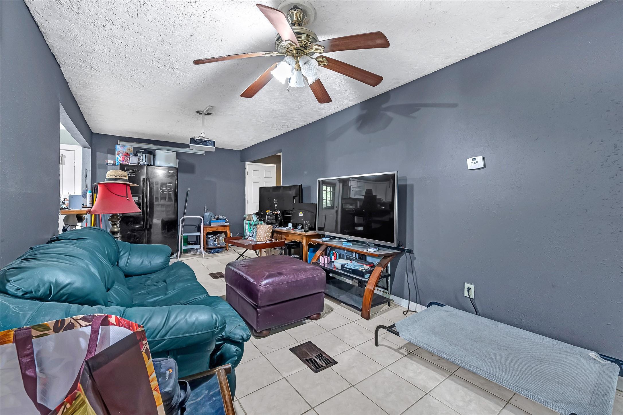Image 3: This cozy living room features tiled flooring, a c
