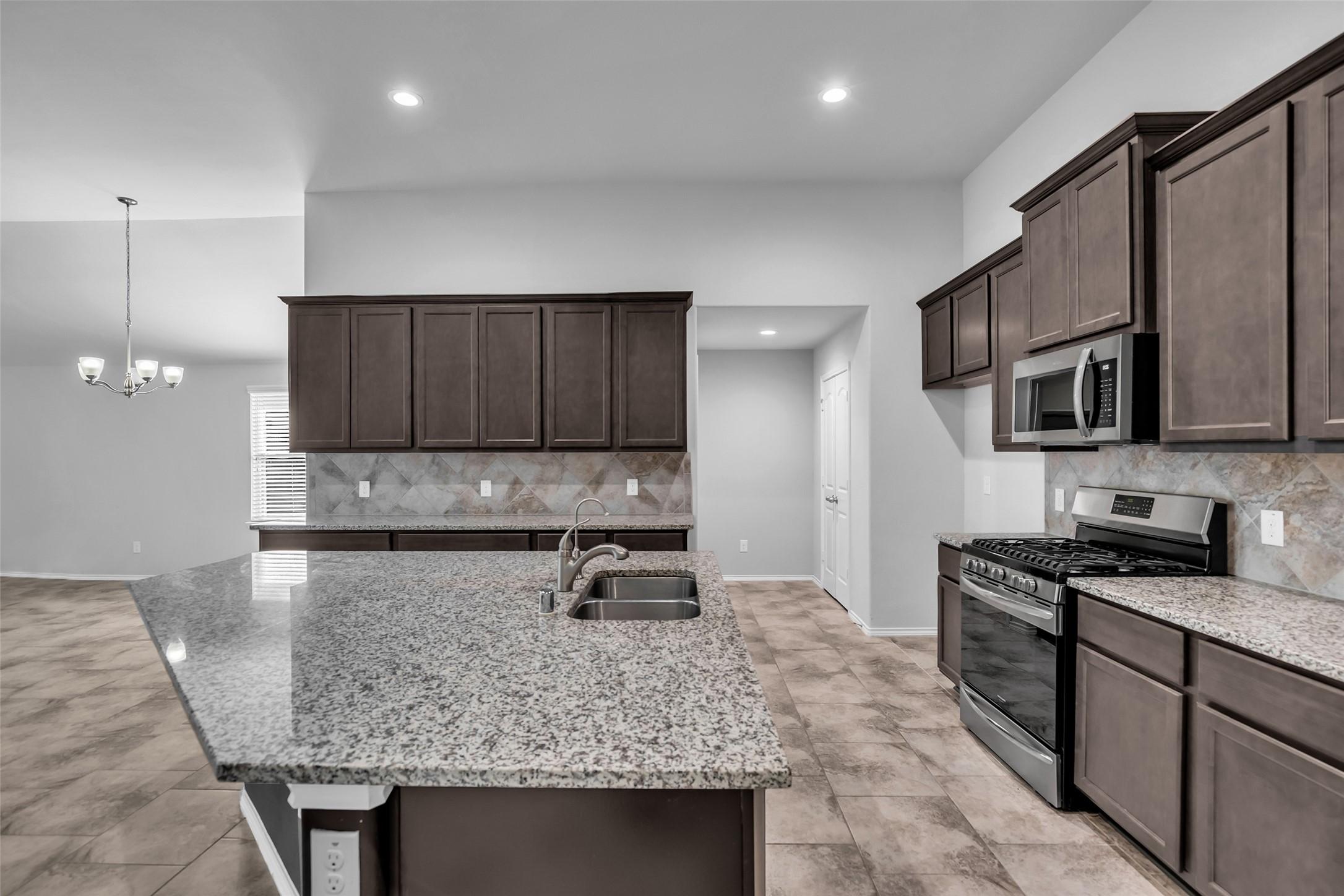 Image 4: The kitchen features granite counters, stainless a