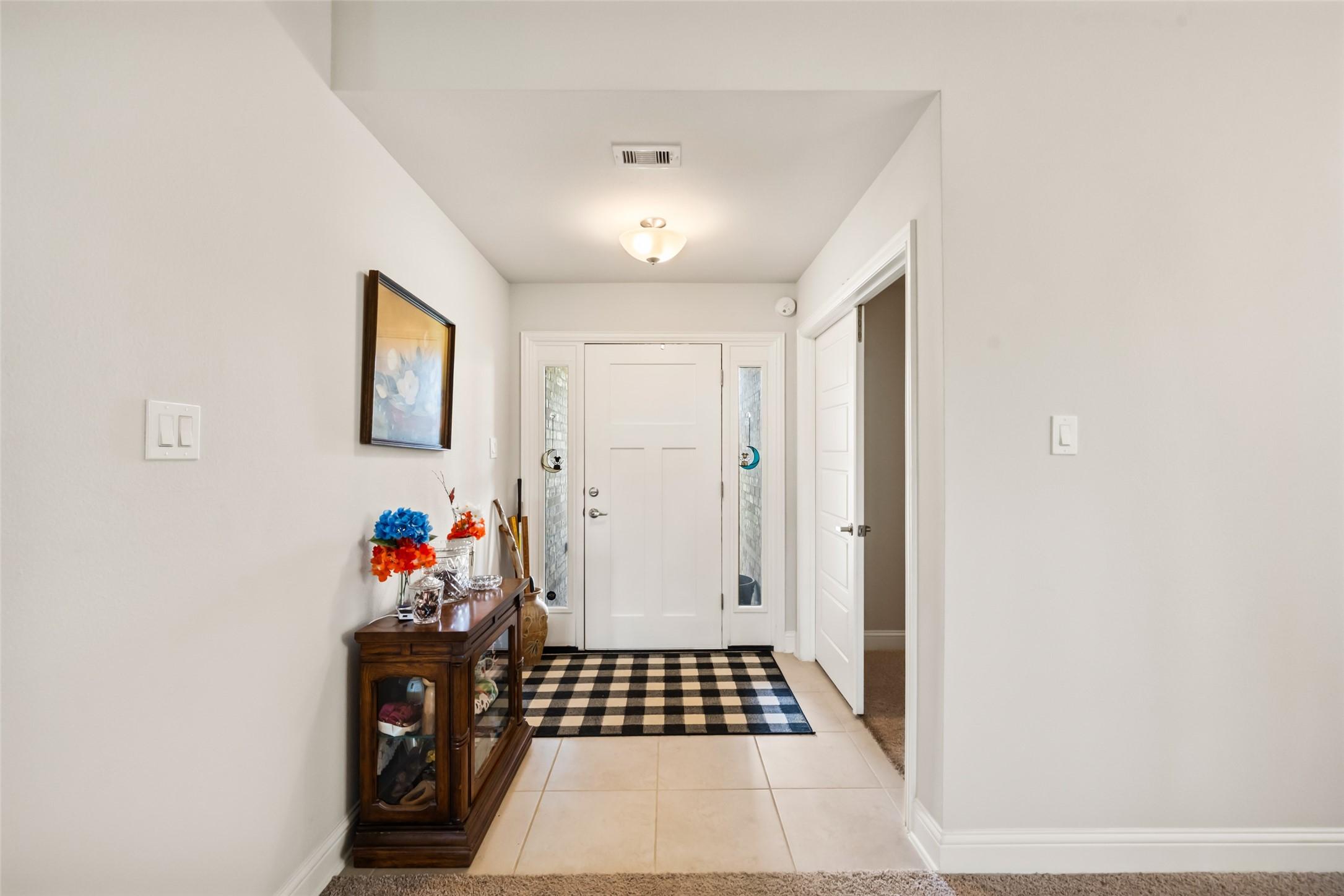 Image 2: Bright entryway with a modern white door featuring