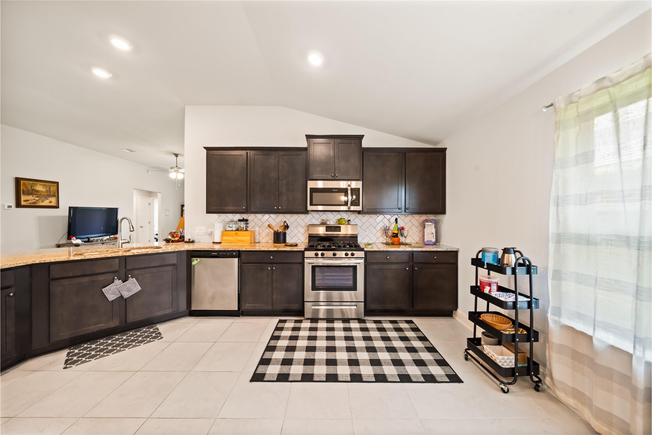 Image 3: This modern kitchen features dark cabinetry, stain