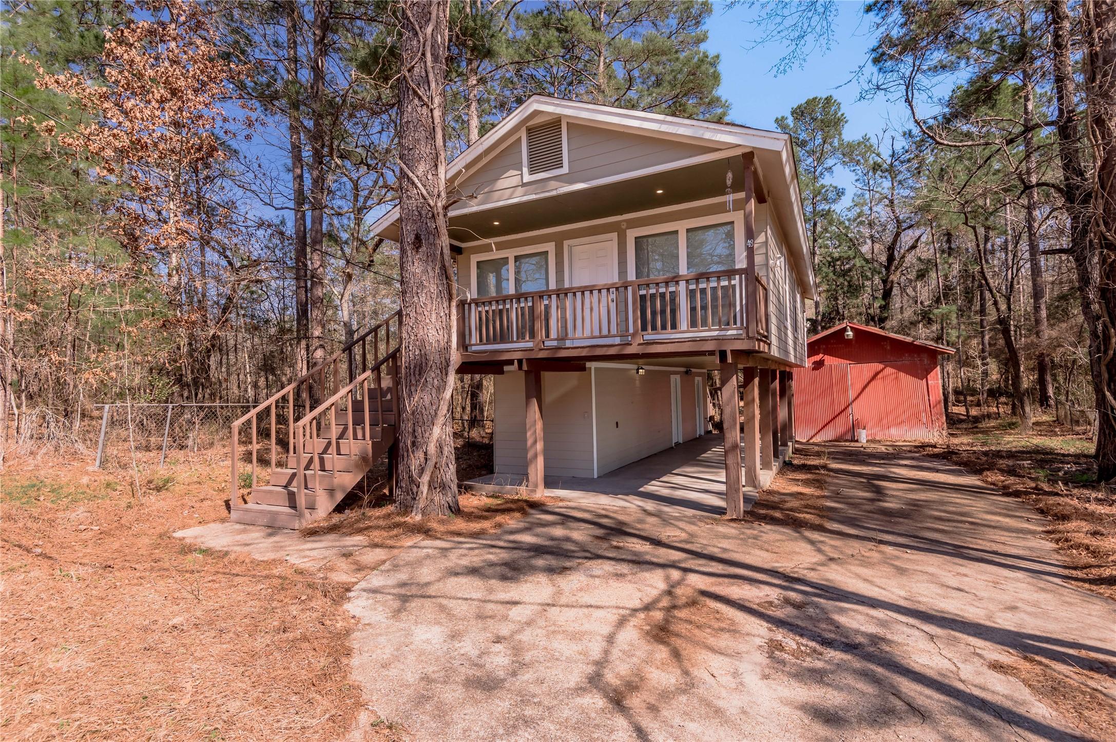 Image 1: This charming elevated home is surrounded by trees