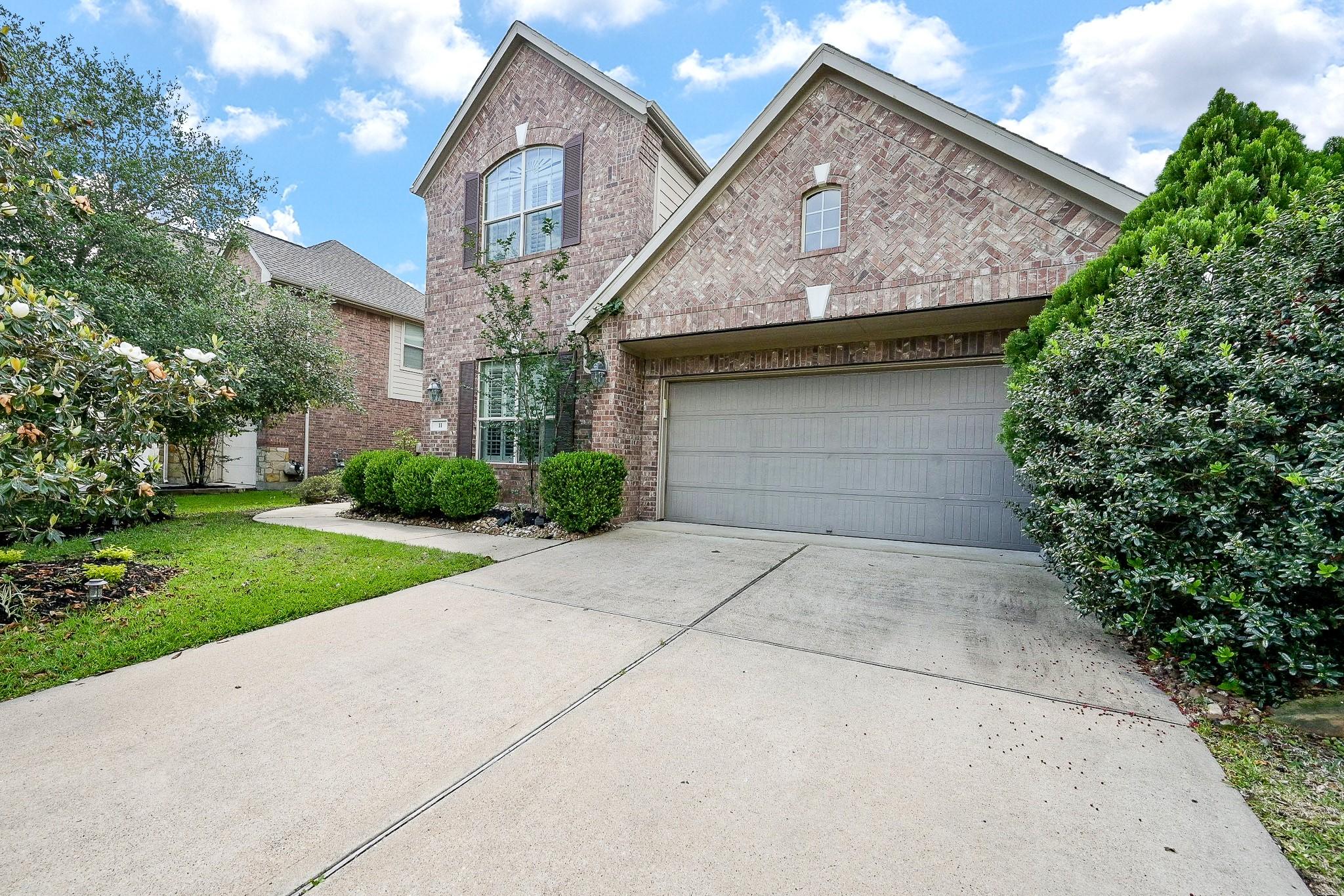 Image 2: Spacious driveway and front entry framed by greene