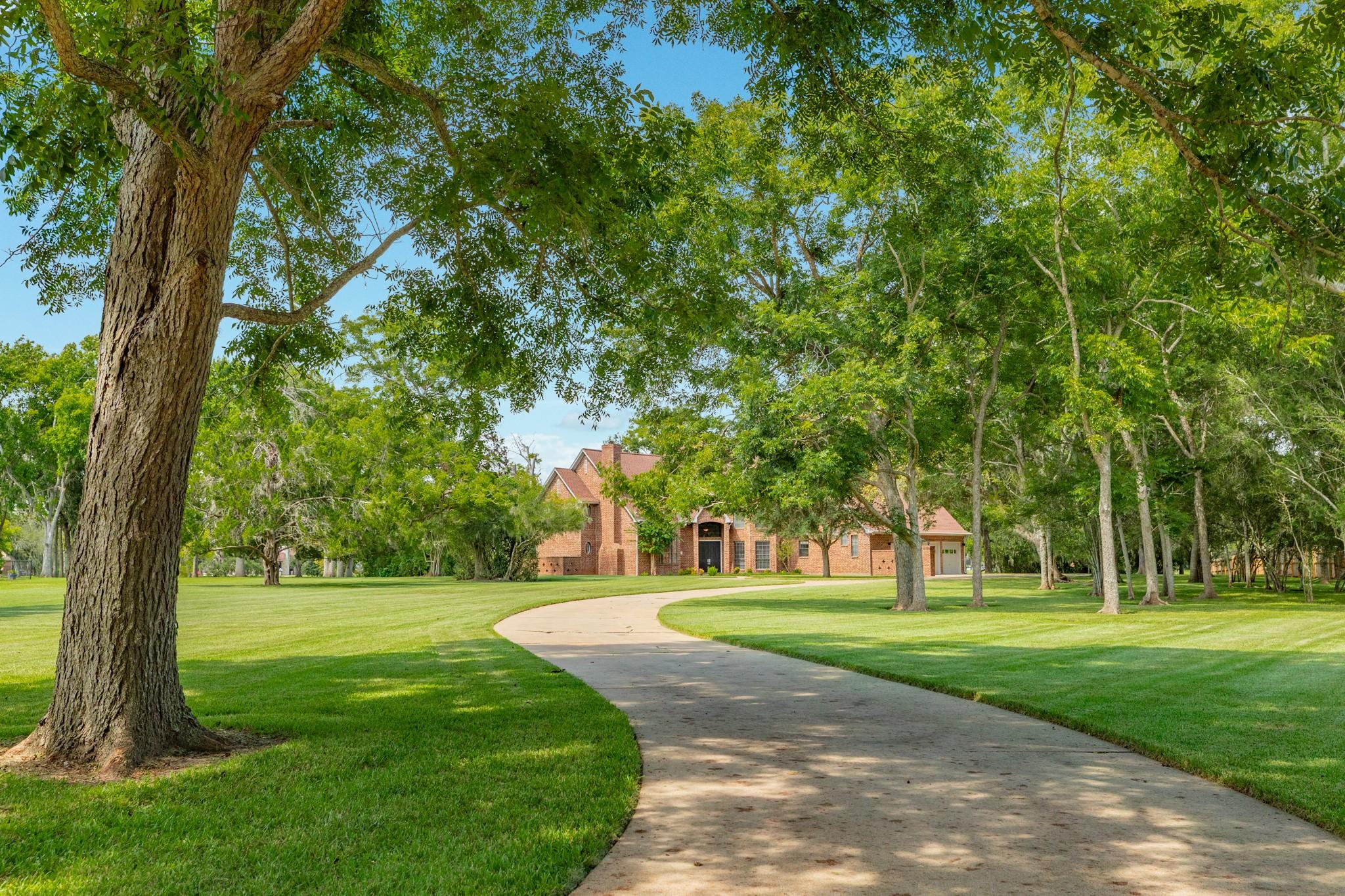Image 3: A long, concrete driveway leads to the residence w