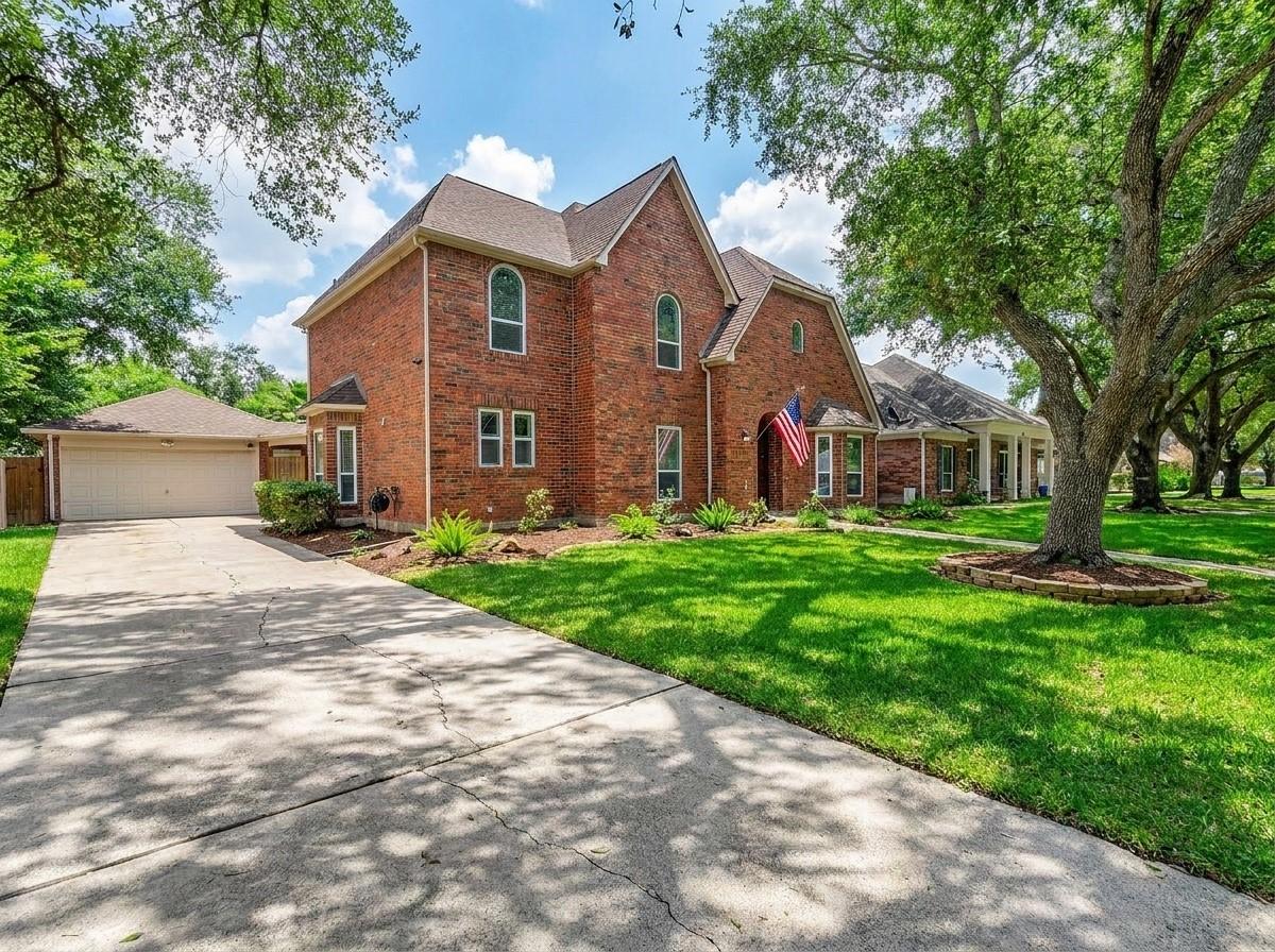 Image 1: Two-story red brick house with a detached garage s