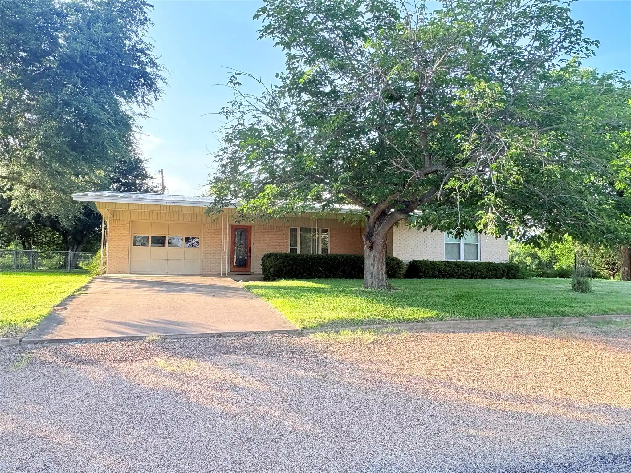 Image 1: Front of home featuring large trees.