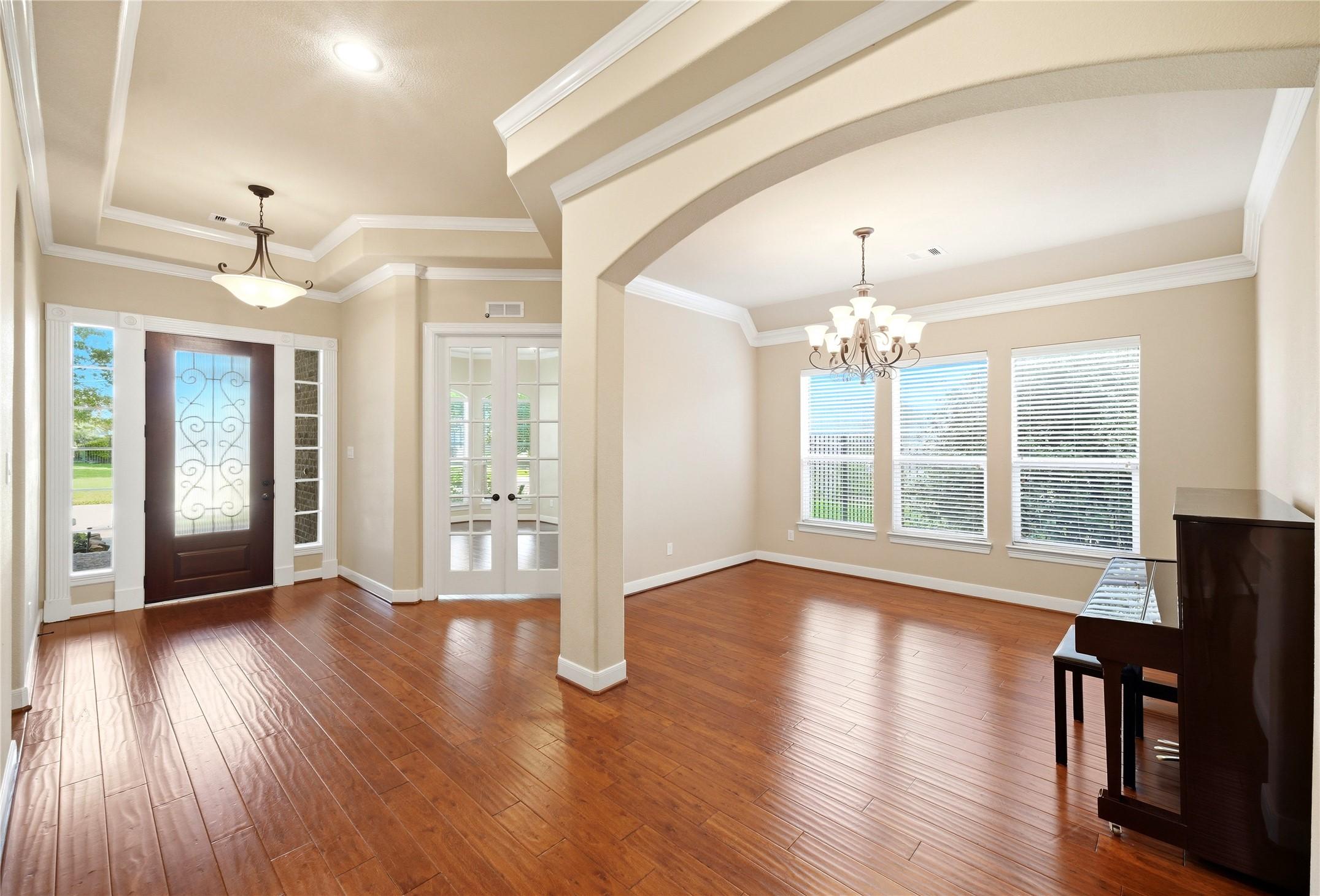 Image 4: A stunning foyer welcomes you with rich hardwood f