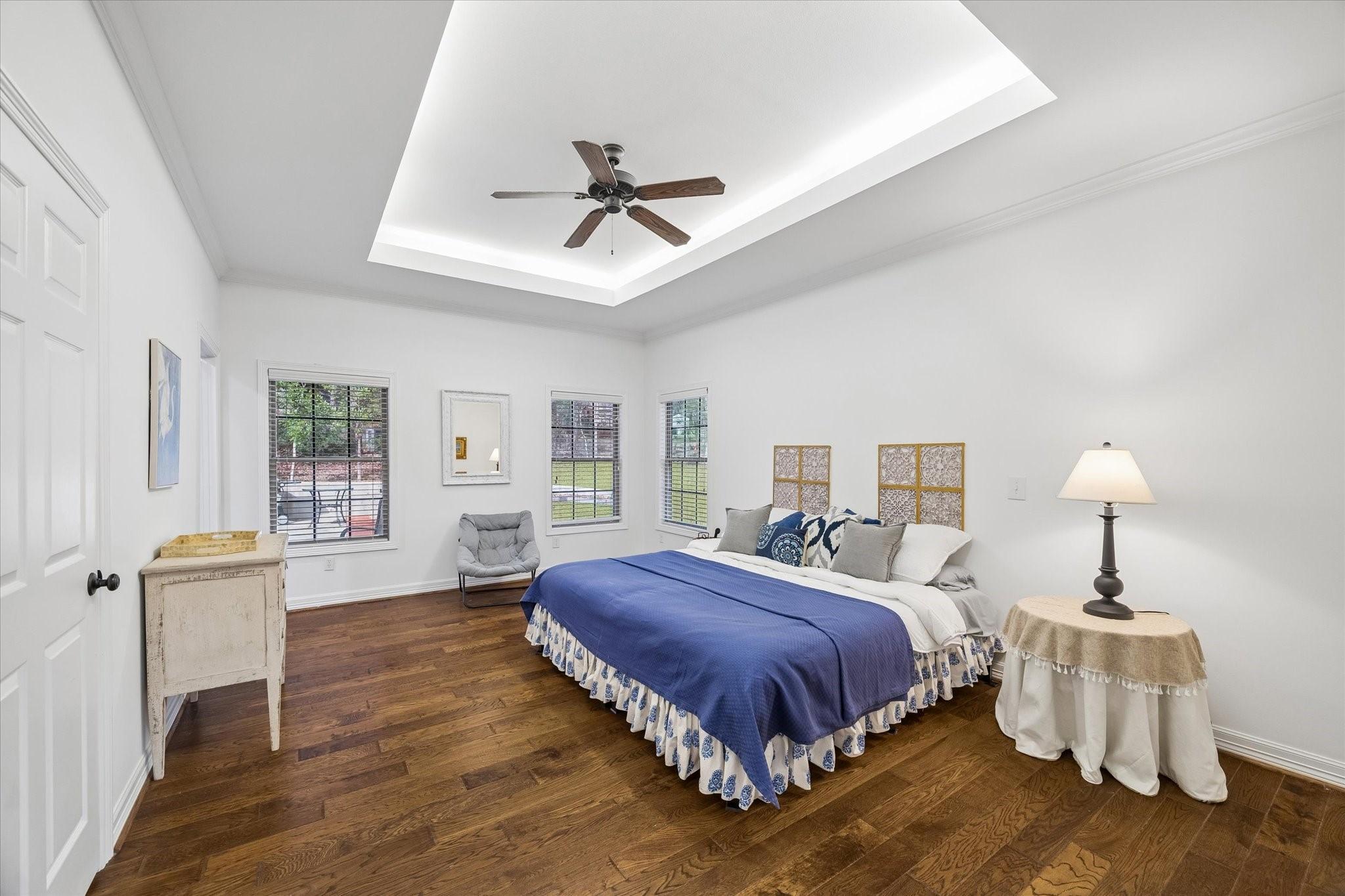 Image 4: The primary bedroom with wood floors and cove ligh