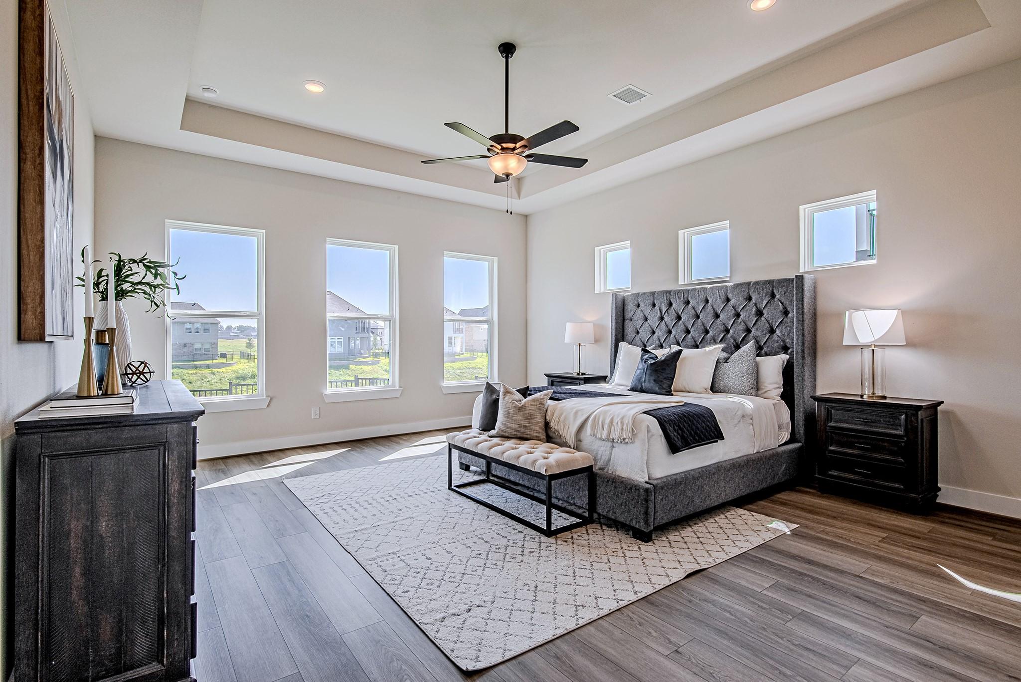 Image 3: Spacious primary bedroom with a tray ceiling, ceil