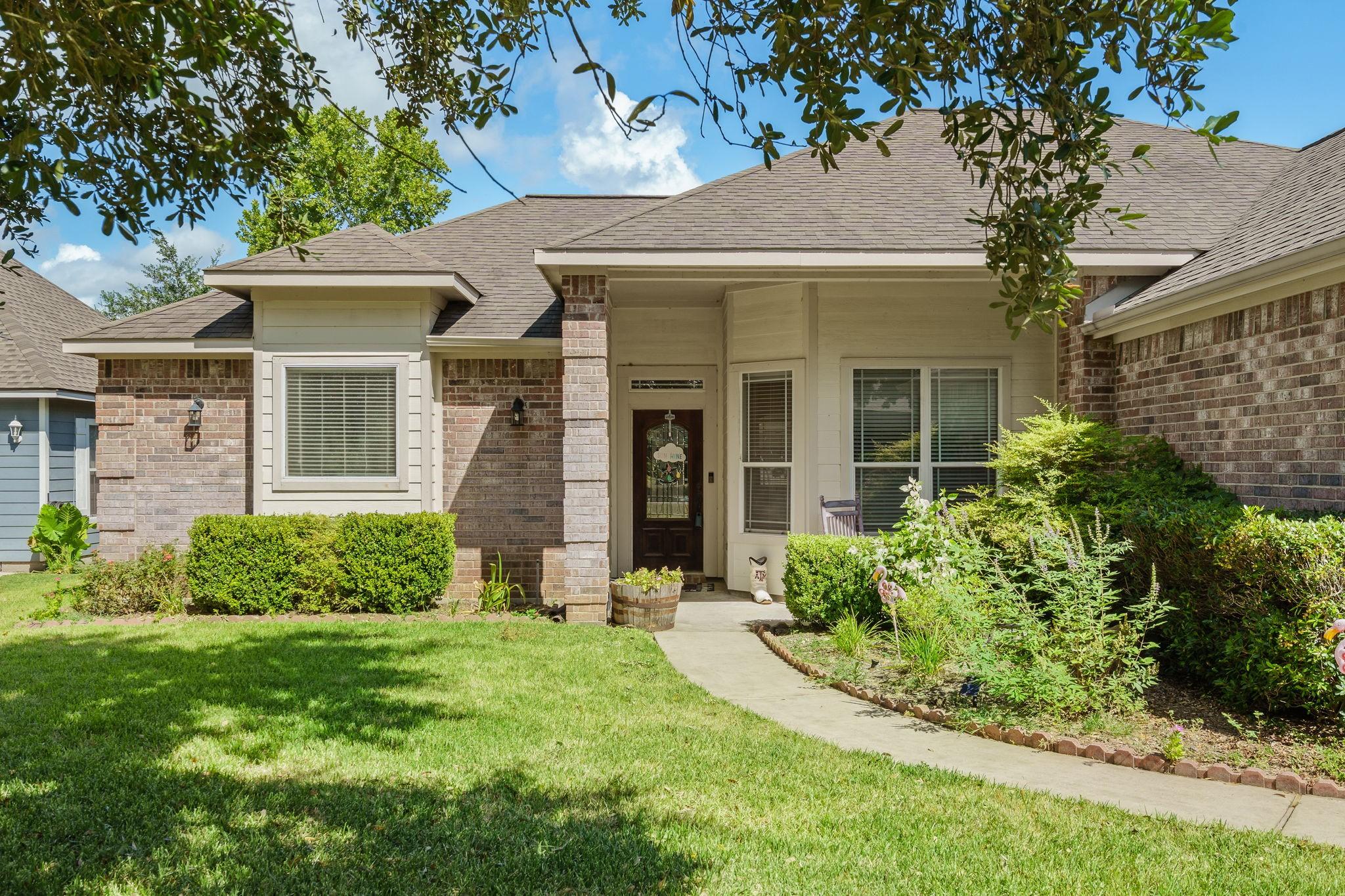 Image 4: Charming front entrance with lush landscaping and