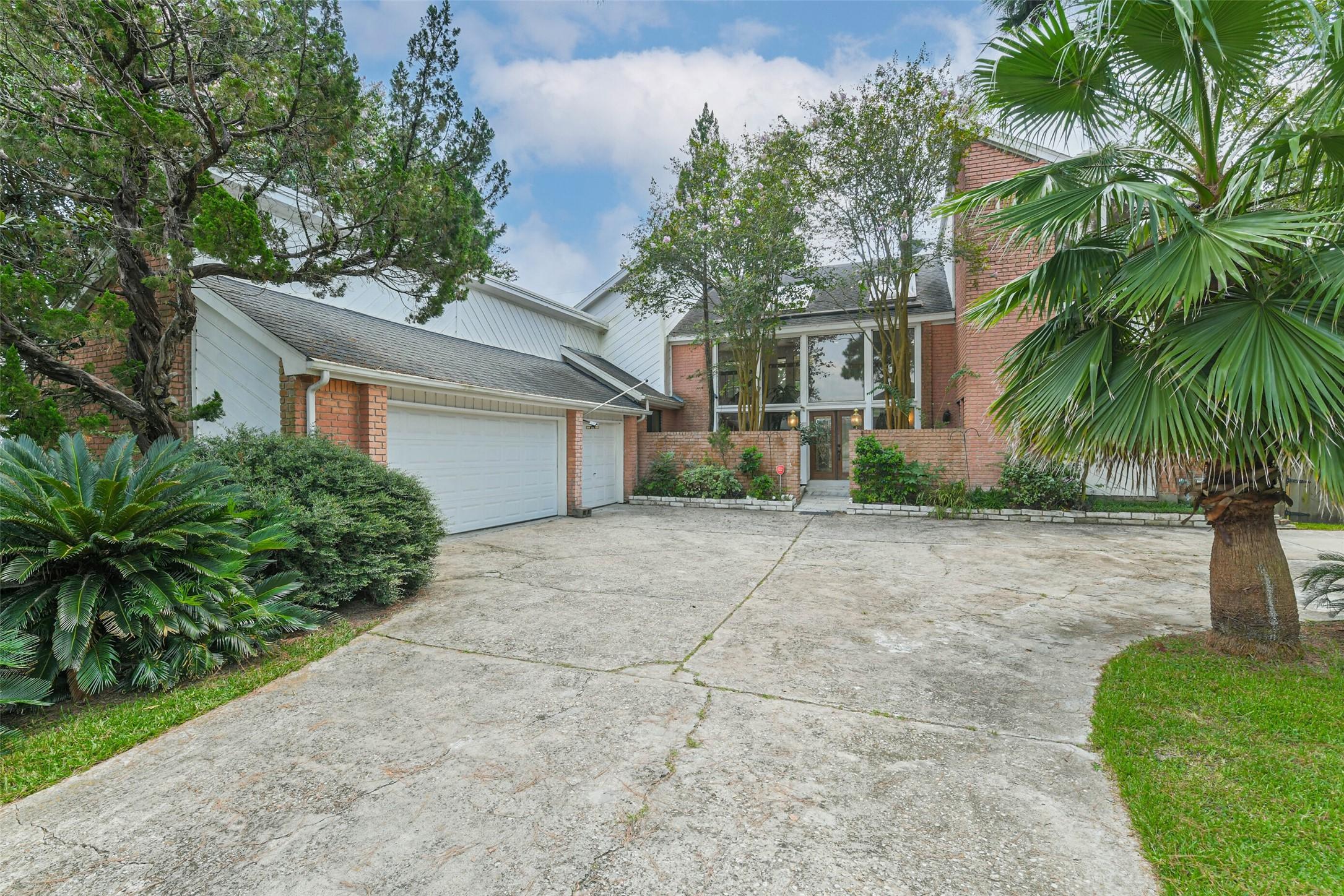 Image 3: A three car garage and extended driveway provide a