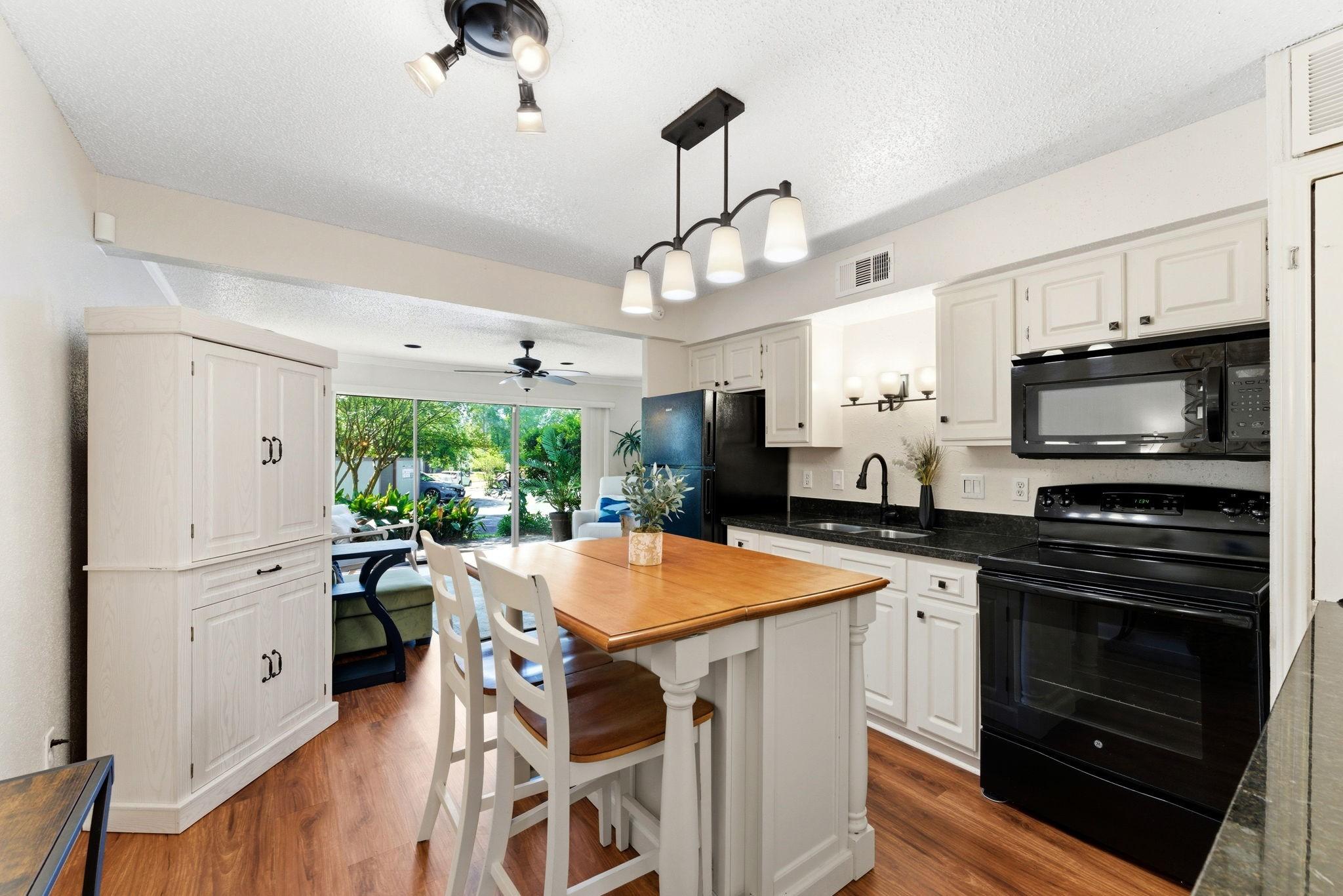 Image 3: This bright kitchen features white cabinetry, blac