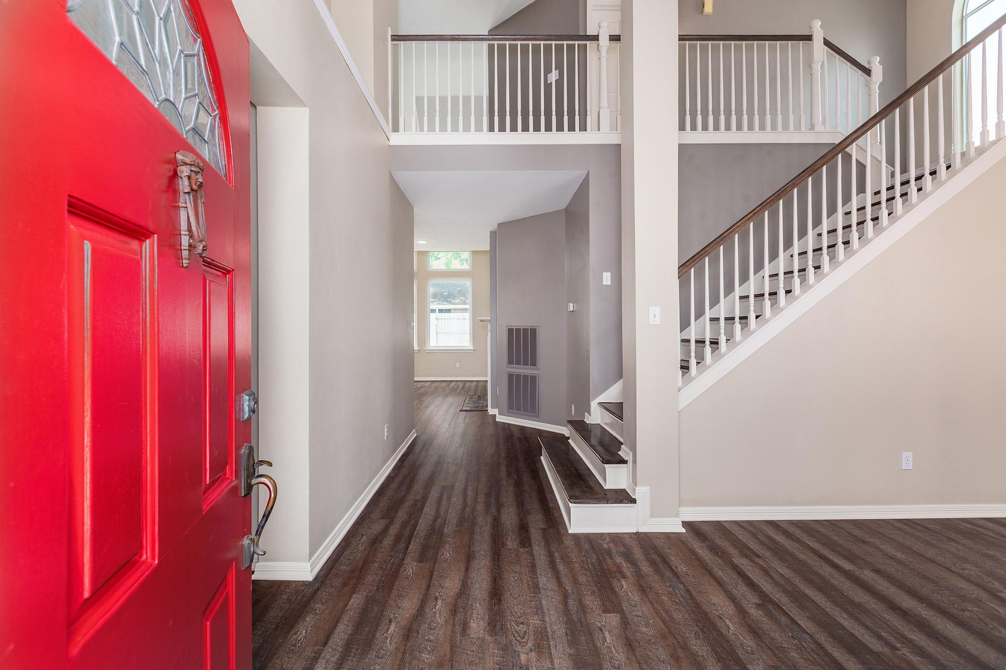 Image 3: Inviting entryway with a striking red door leads t