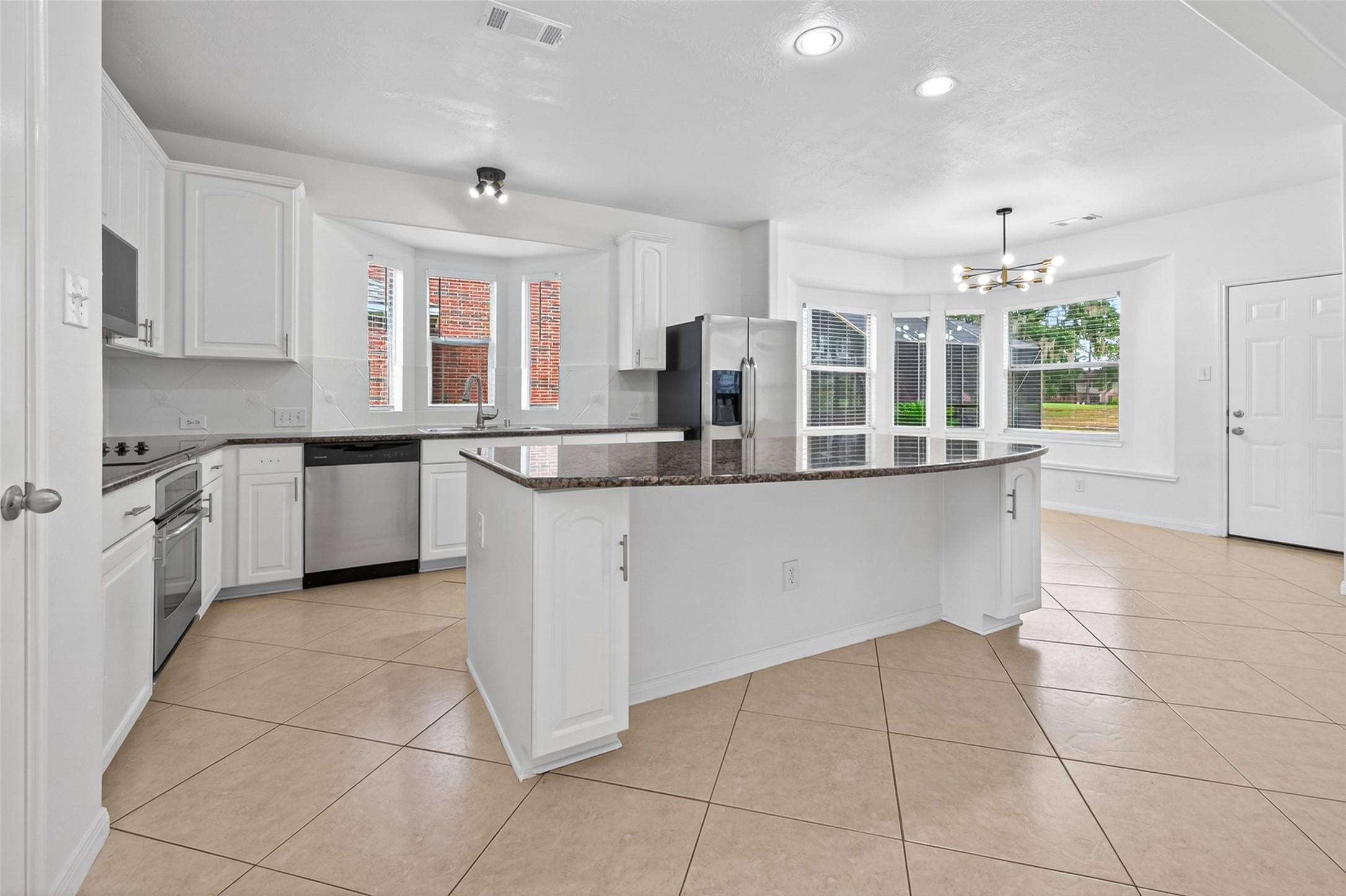 Image 4: Spacious kitchen featuring a large granite island,