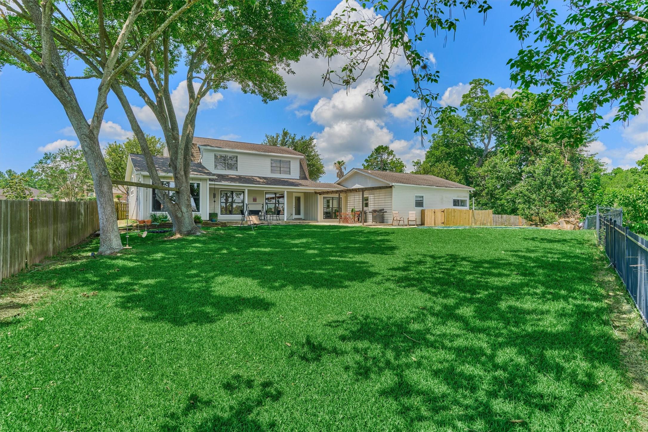 Image 1: Nestled beneath a canopy of mature trees, the home