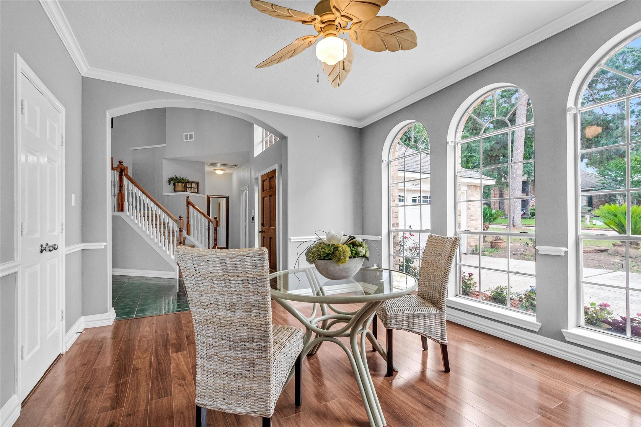 Image 2: Bright dining area with large arched windows, wood