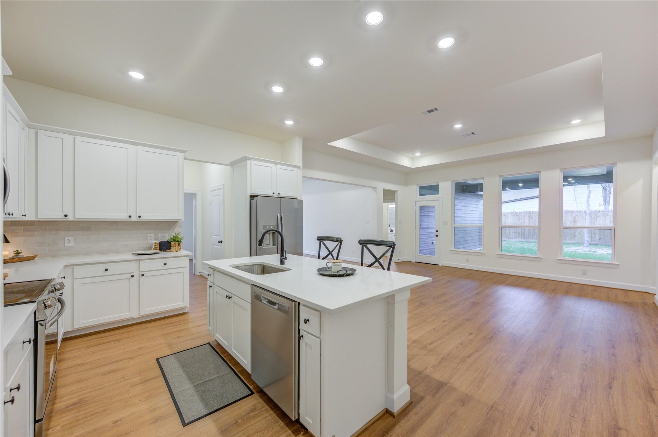 Image 4: This spacious kitchen has sleek white cabinetry, a