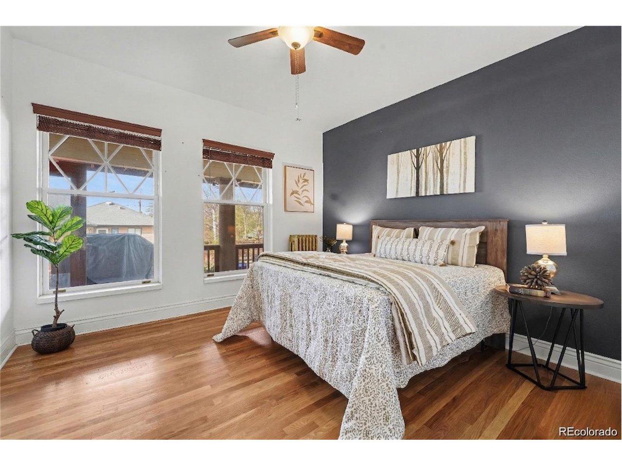 Image 3: Spacious bedroom with a stylish accent wall and large windows! Offers a light-filled, comfortable layout with timeless character!