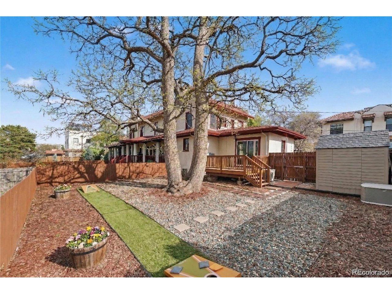 Image 4: Fully fenced backyard with a gate and a decades-old tree providing generous shade, a spacious deck, and low-maintenance landscaping! Includes a storage shed and a defined lawn area perfect for outdoor activities!
