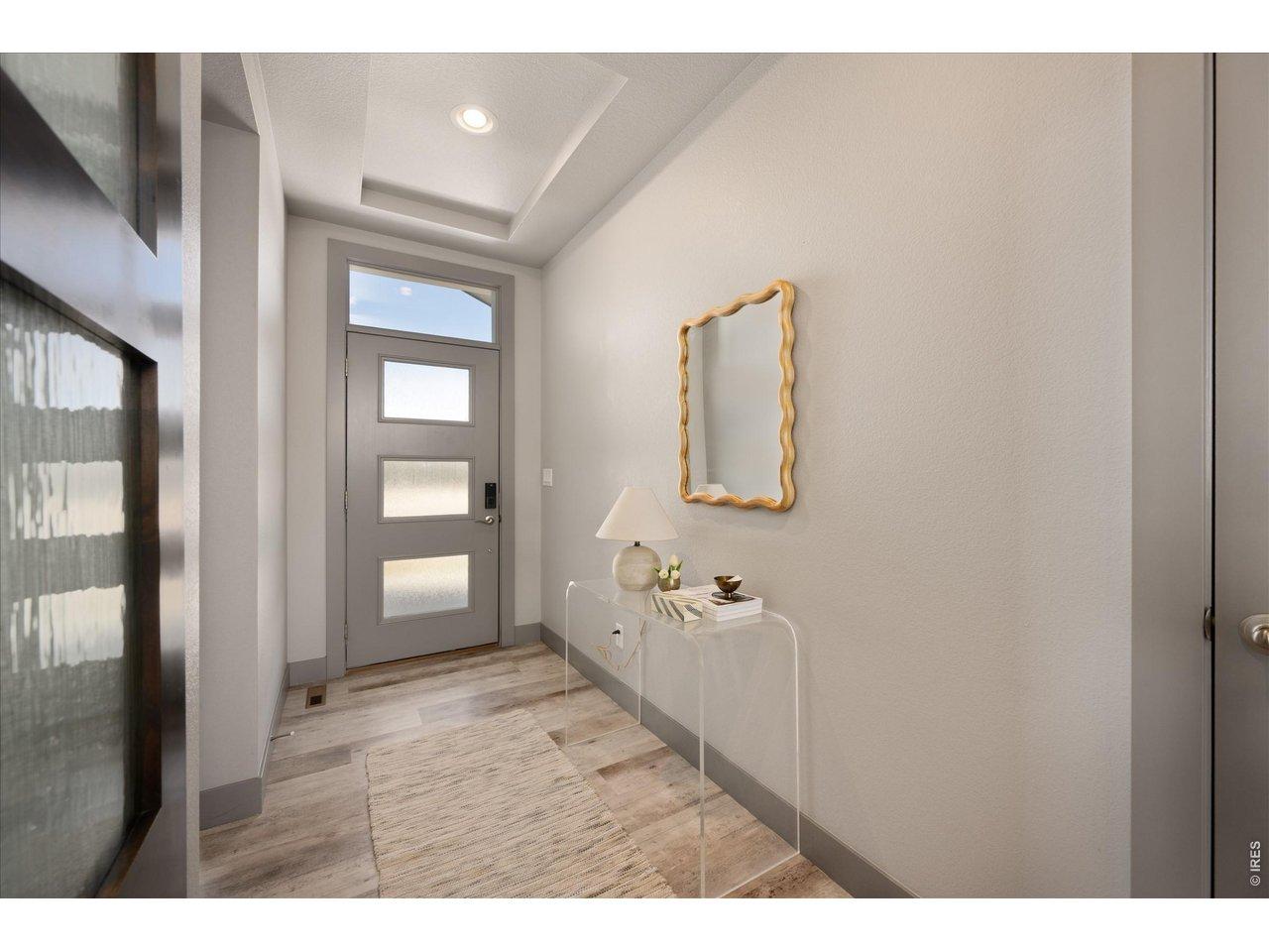 Image 3: Step into an inviting entryway featuring a beautifully crafted coffered ceiling and an elegant transom window above the doorway. The space is enhanced by luxurious vinyl flooring, offering both style and durability.