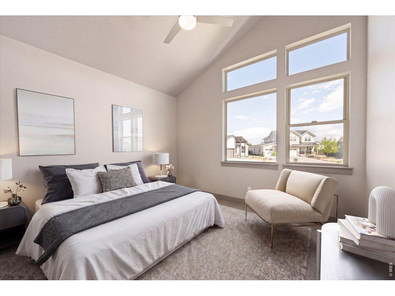Image 4: The front secondary bedroom is thoughtfully staged, showcasing impressive vaulted ceilings and large windows that fill the room with natural light. Additionally, it boasts a spacious walk-in closet, providing ample storage and convenience.