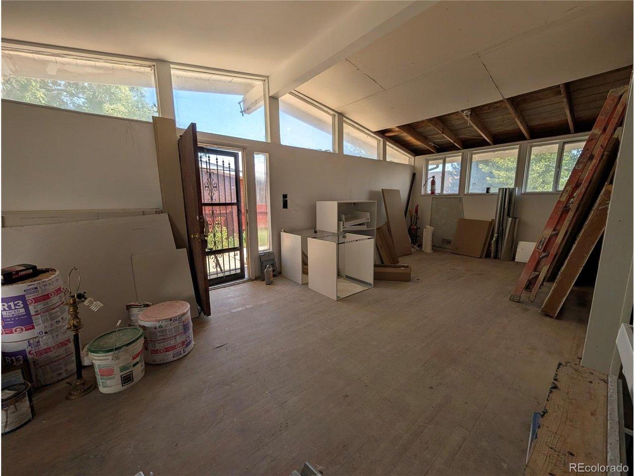 Image 2: Main living area with large windows, natural light, and vaulted ceiling detail.