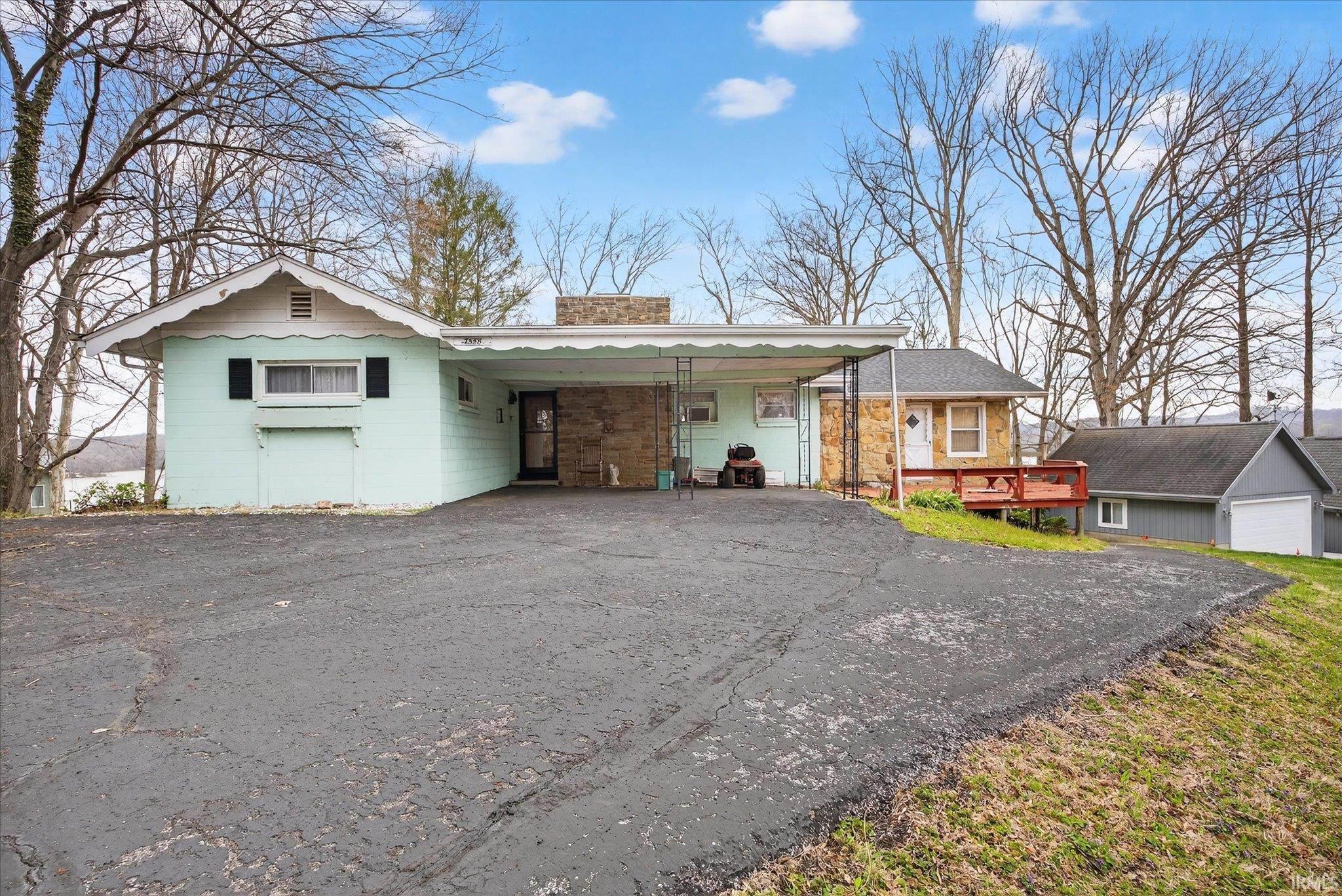 Image 1: Ranch-style house with a chimney, a carport, asphalt driveway, and a wooden deck, Front Of Structure Image 1: Ranch-style house with a chimney, a carport, asphalt driveway, and a wooden deck, Front Of Structure