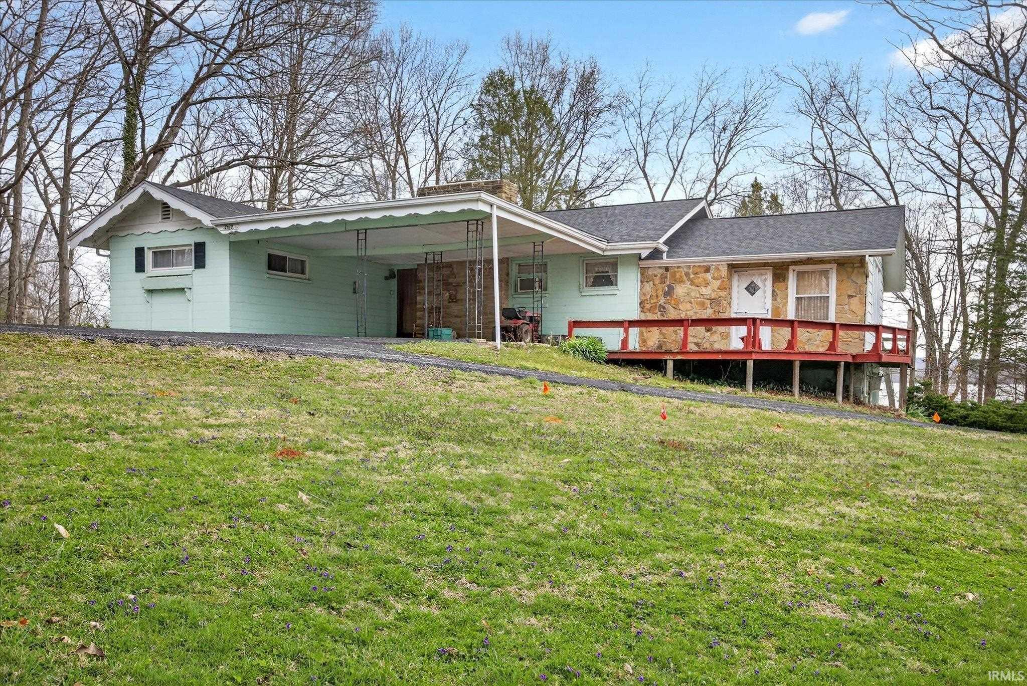 Image 2: View of front of house with a front lawn, stone siding, a carport, and a chimney, Front Of Structure Image 2: View of front of house with a front lawn, stone siding, a carport, and a chimney, Front Of Structure