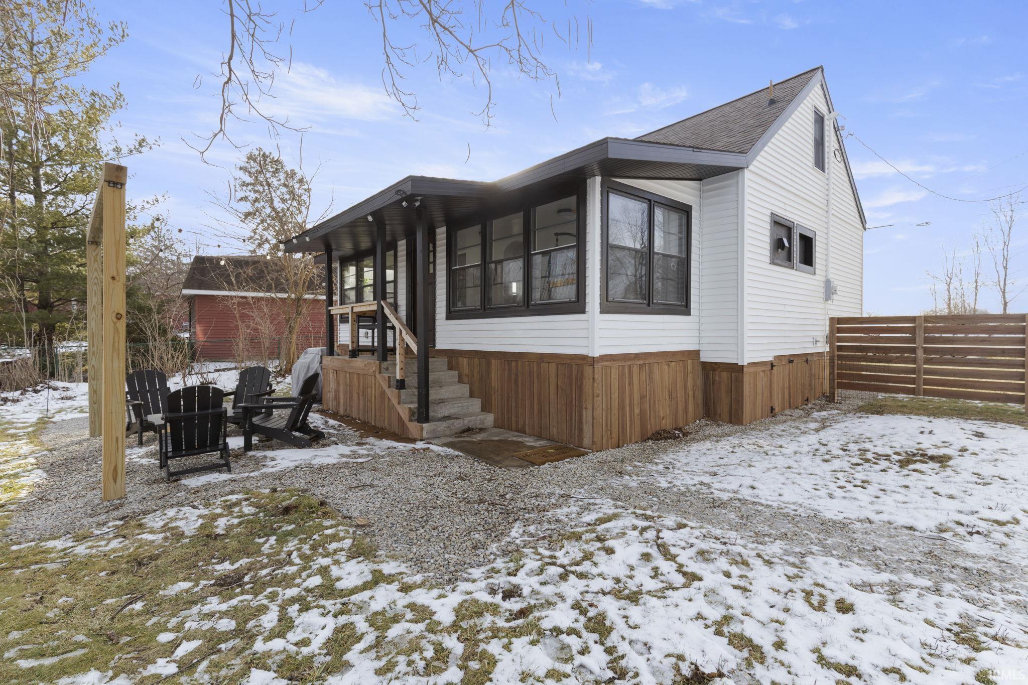 Image 1: View of snow covered exterior with a sunroom, a shingled roof, and a patio area, Side Of Structure