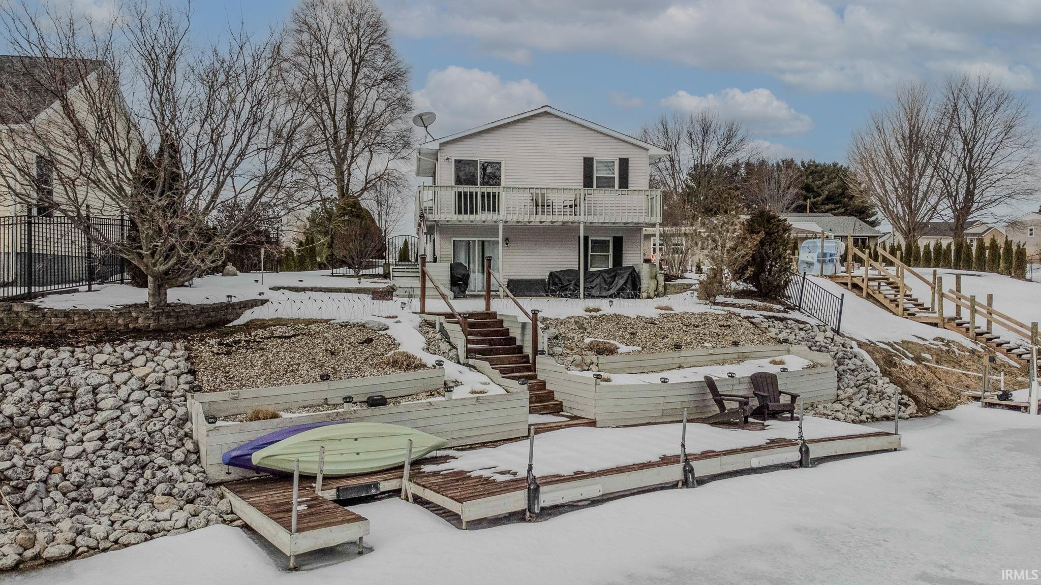 Image 1: Snow covered house with stairs and a deck, Back Of Structure