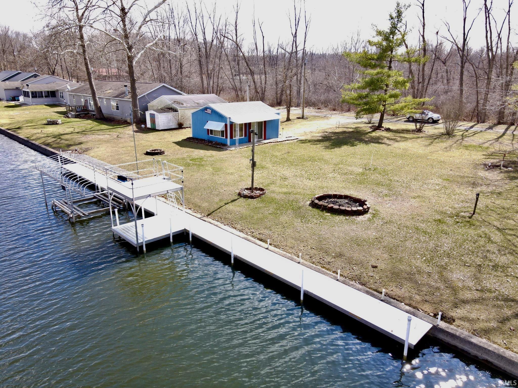 Image 1: Dock featuring a yard, a water view, a residential view, an outdoor fire pit, and boat lift, Dock