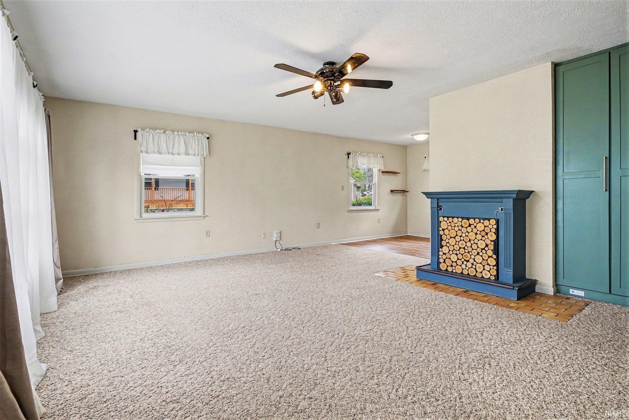 Image 1: Unfurnished living room featuring light carpet, a fireplace, and ceiling fan, Living Room