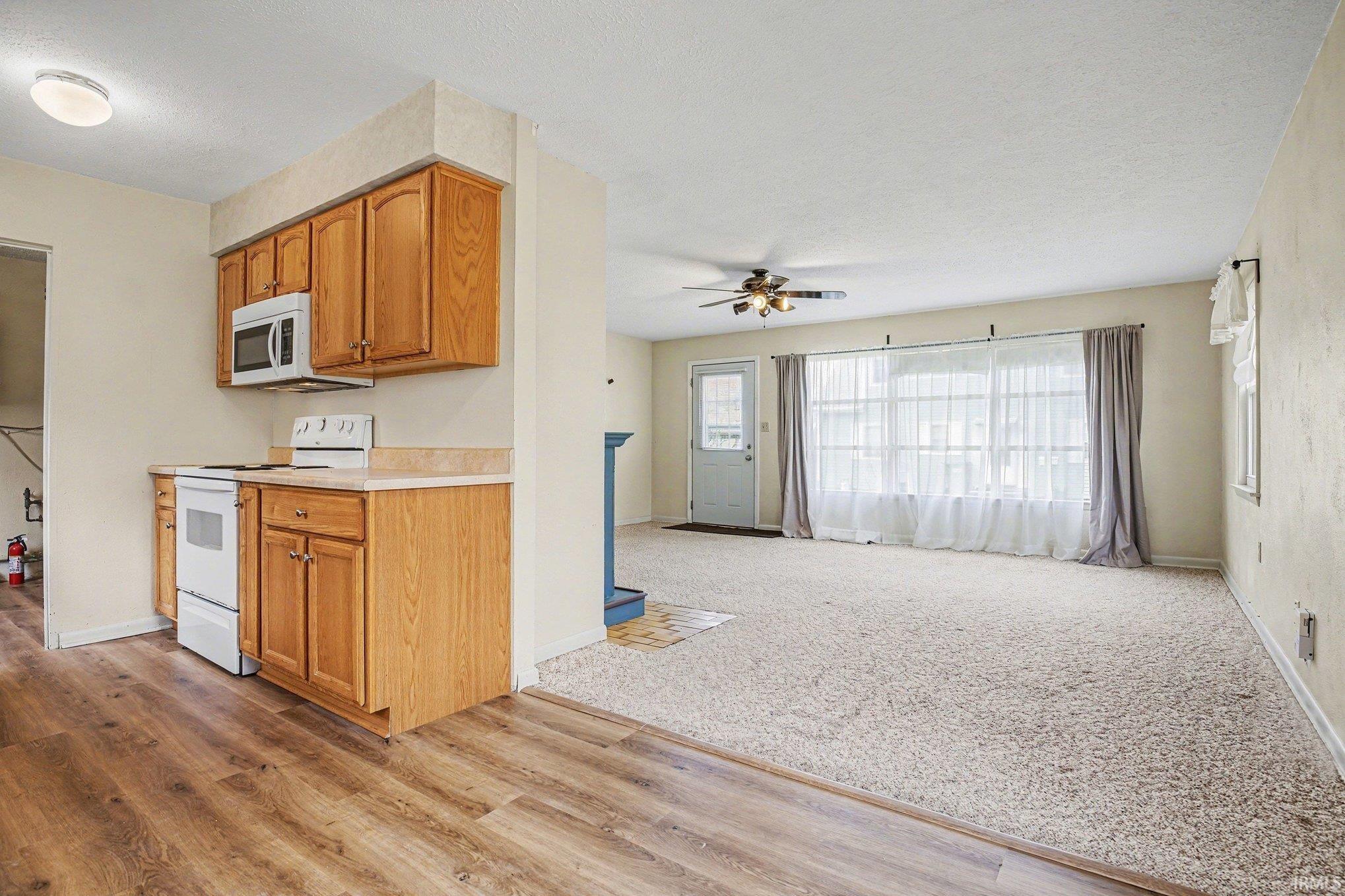 Image 2: Kitchen with light countertops, electric stove, wood finish cabinets, a ceiling fan, and a textured ceiling, Kitchen