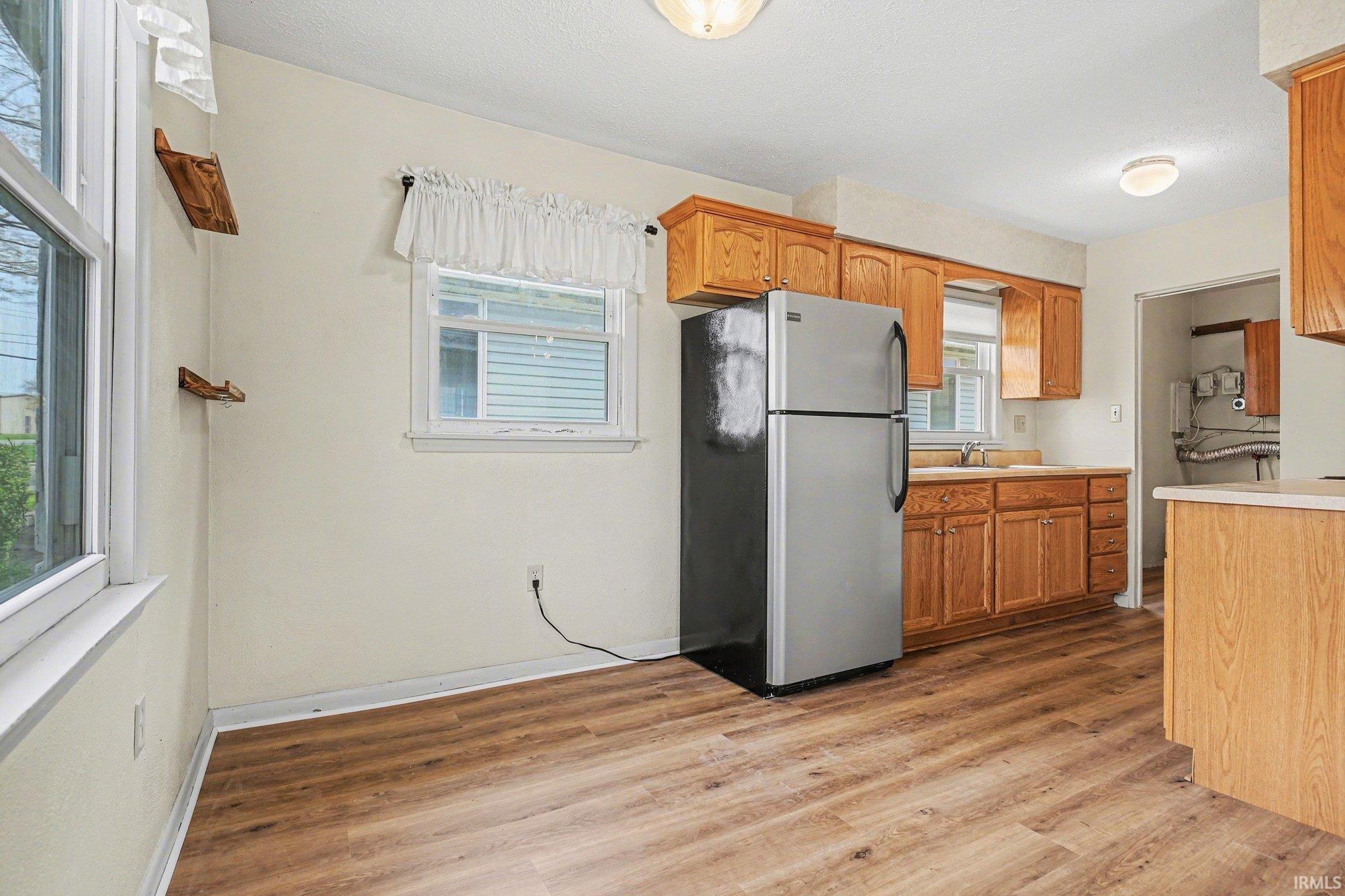 Image 3: Kitchen featuring freestanding refrigerator, light countertops, light wood-style flooring, and wood finish cabinets, Kitchen