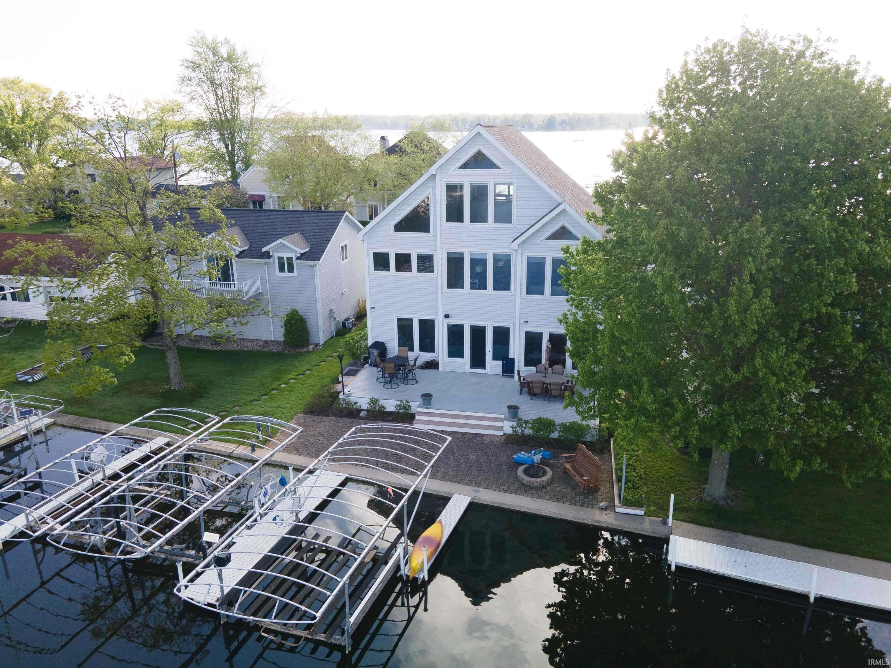 Image 0: Waterfront property featuring a multi-level structure with extensive window placements, a spacious patio, and multiple boat lifts, Aerial View Image 0: Waterfront property featuring a multi-level structure with extensive window placements, a spacious patio, and multiple boat lifts, Aerial View