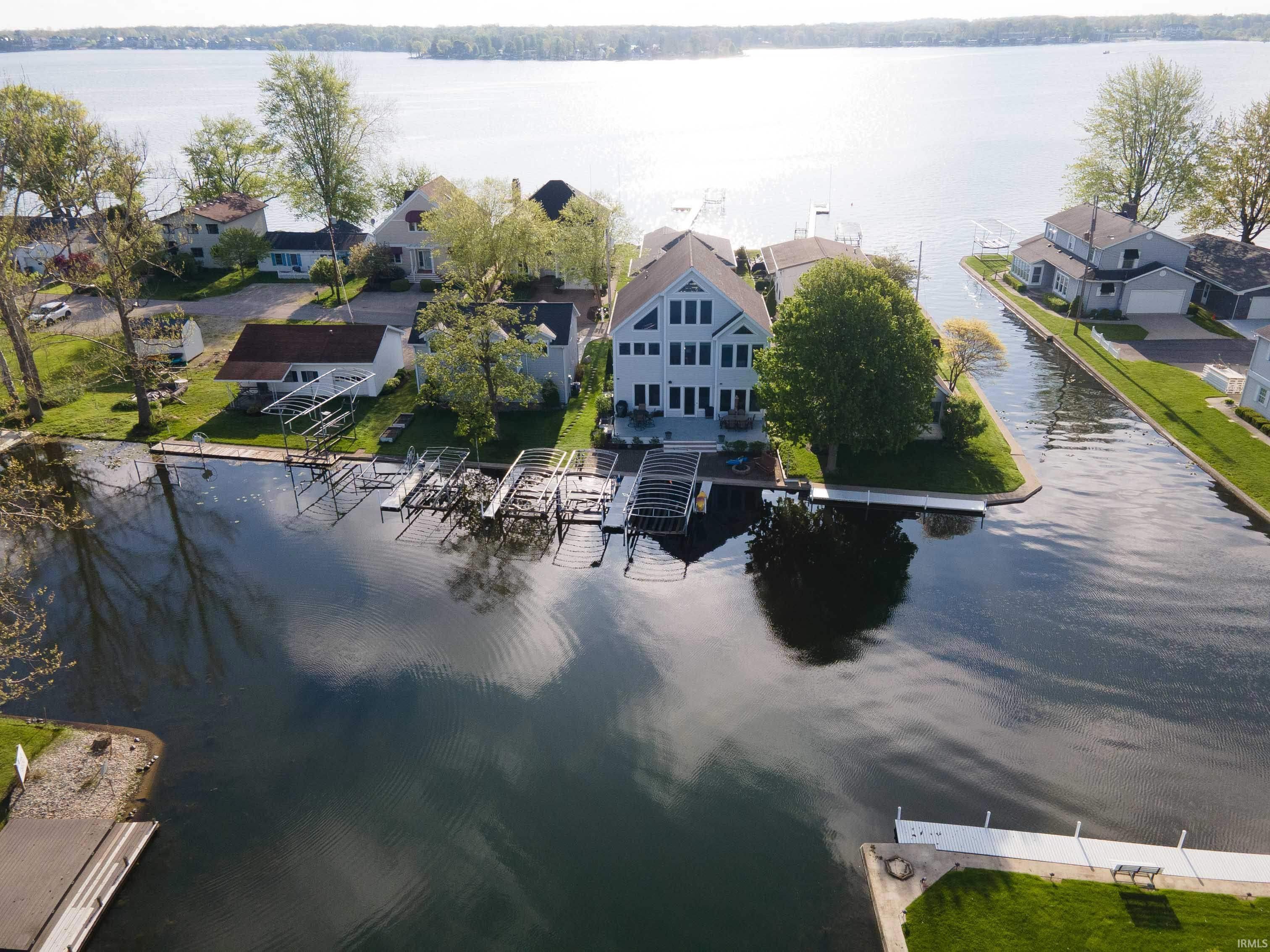 Image 1: Waterfront property featuring a multi-story residence with multiple windows, boat docks, and a channel providing access to the main lake, Aerial View Image 1: Waterfront property featuring a multi-story residence with multiple windows, boat docks, and a channel providing access to the main lake, Aerial View