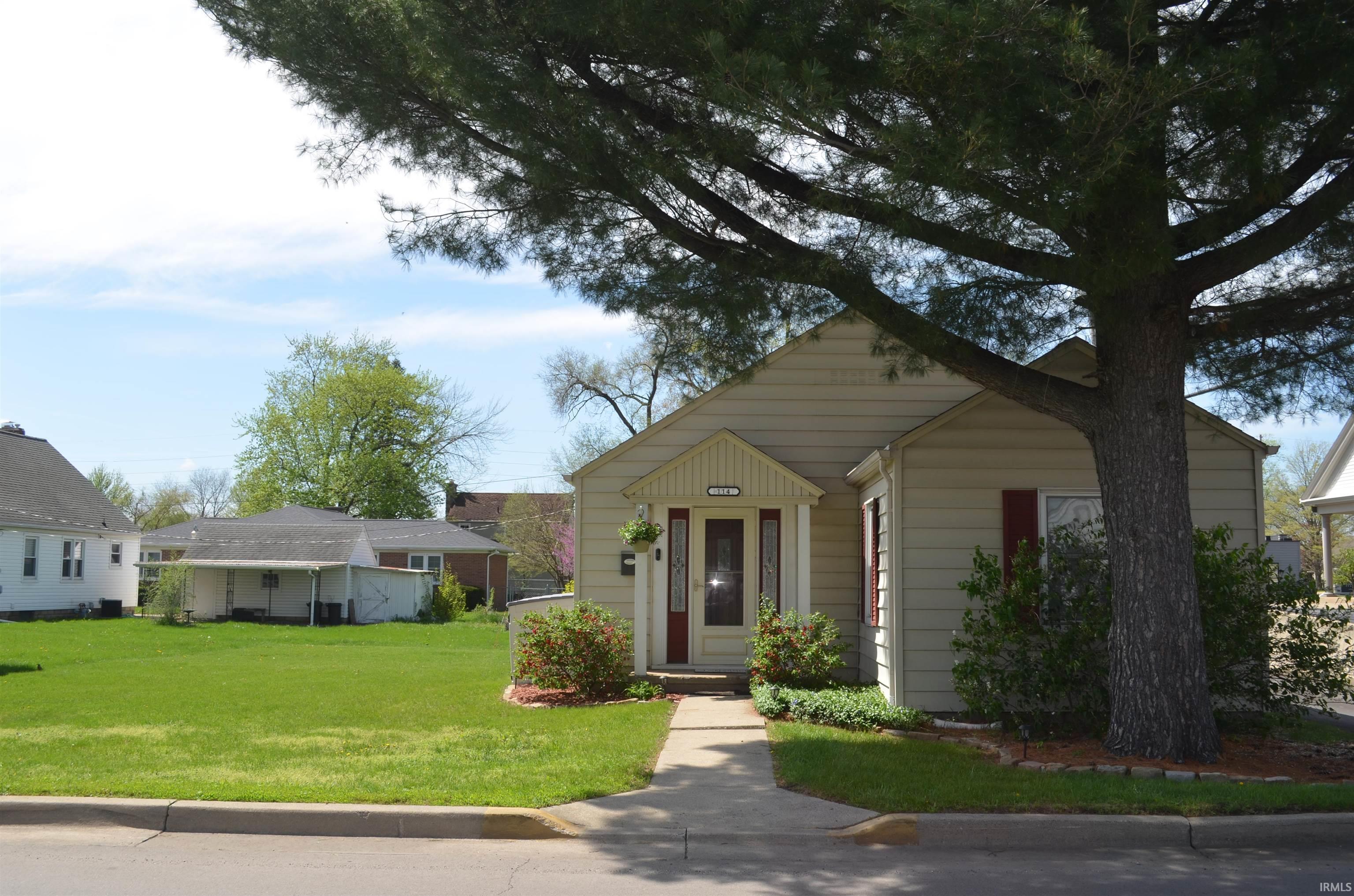 Image 1: Cream-colored siding exterior with a prominent front entry featuring a red door with glass inserts and a covered porch, Front Of Structure Image 1: Cream-colored siding exterior with a prominent front entry featuring a red door with glass inserts and a covered porch, Front Of Structure