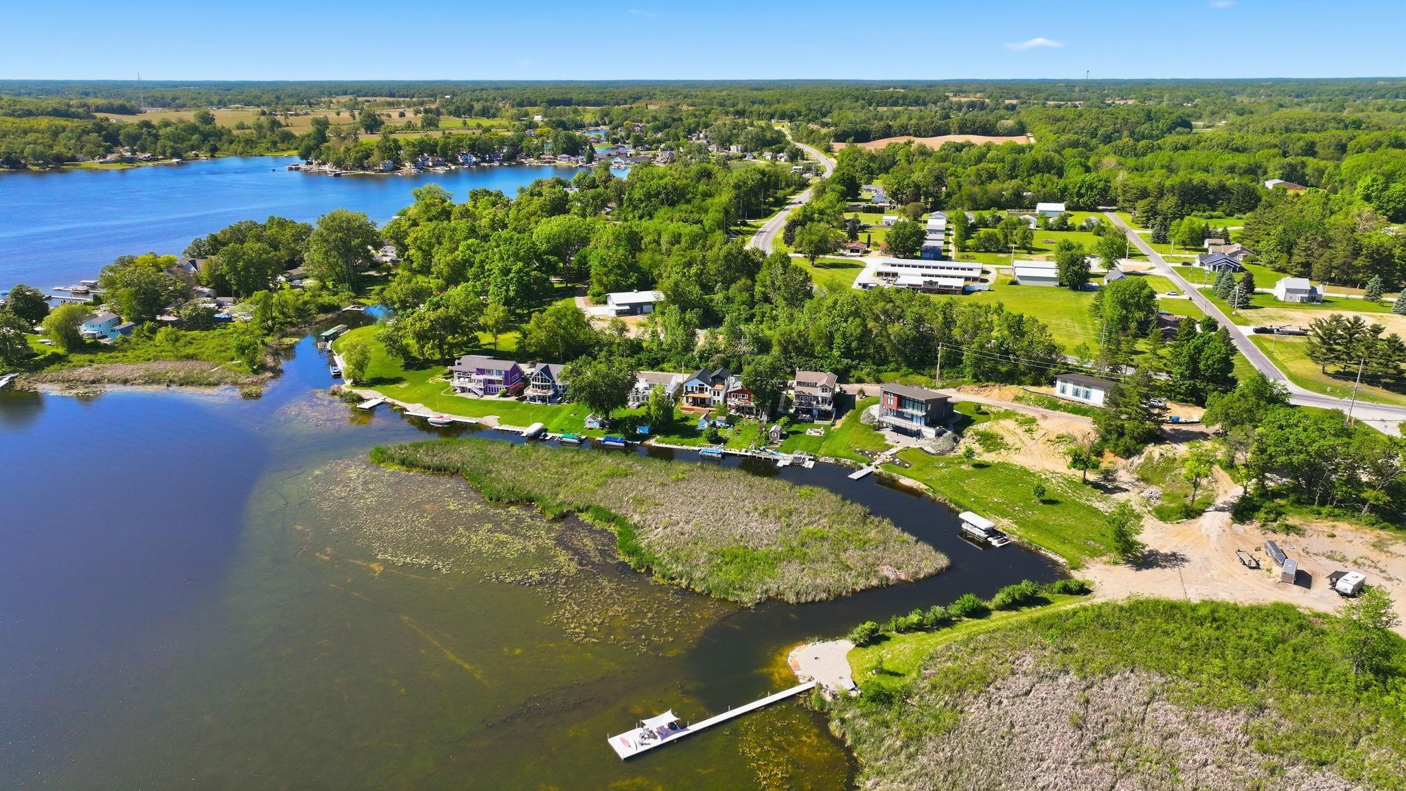 Image 3: Expansive waterfront property featuring a private dock, direct lake access, and surrounding mature trees, Aerial View Image 3: Expansive waterfront property featuring a private dock, direct lake access, and surrounding mature trees, Aerial View
