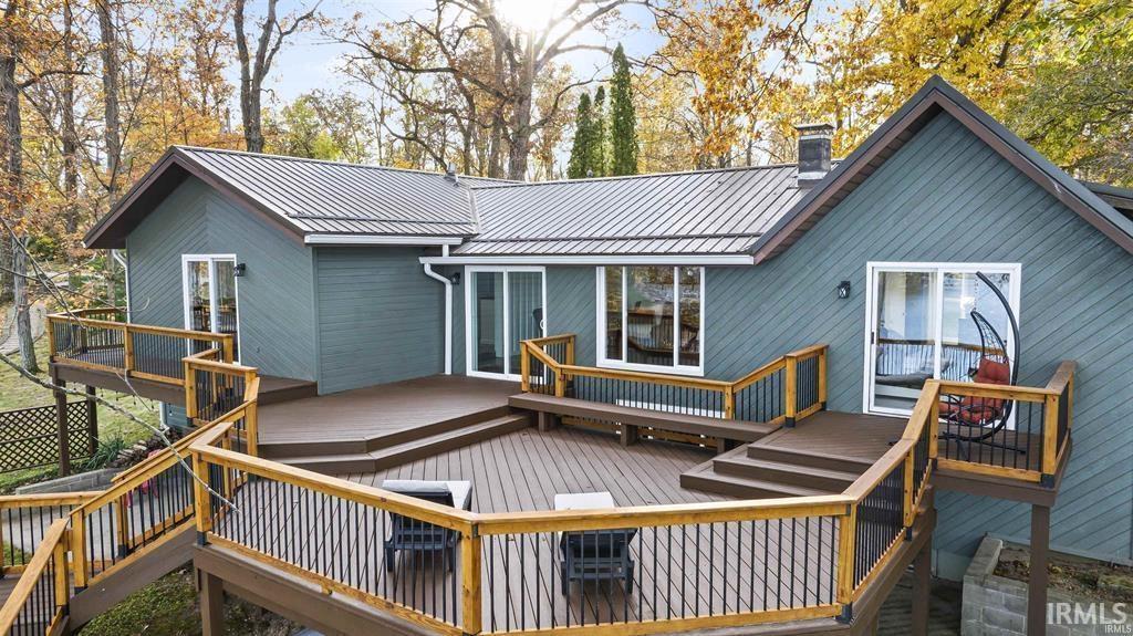 Image 1: Back of house with a wooden deck, a chimney, and a metal roof, Back Of Structure