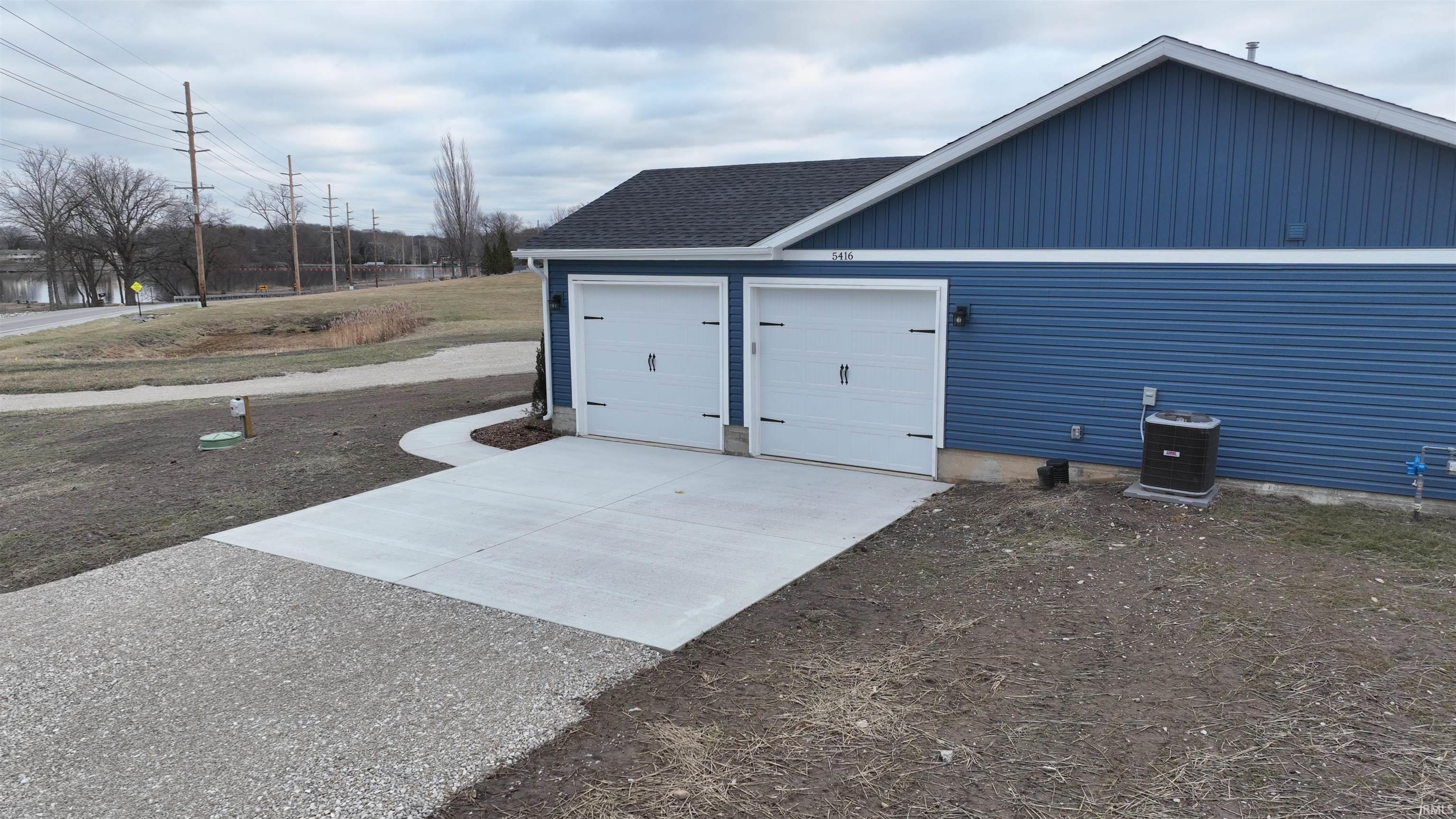 Image 1: View of side of home with driveway, roof with shingles, a garage, and an outdoor structure, Side Of Structure