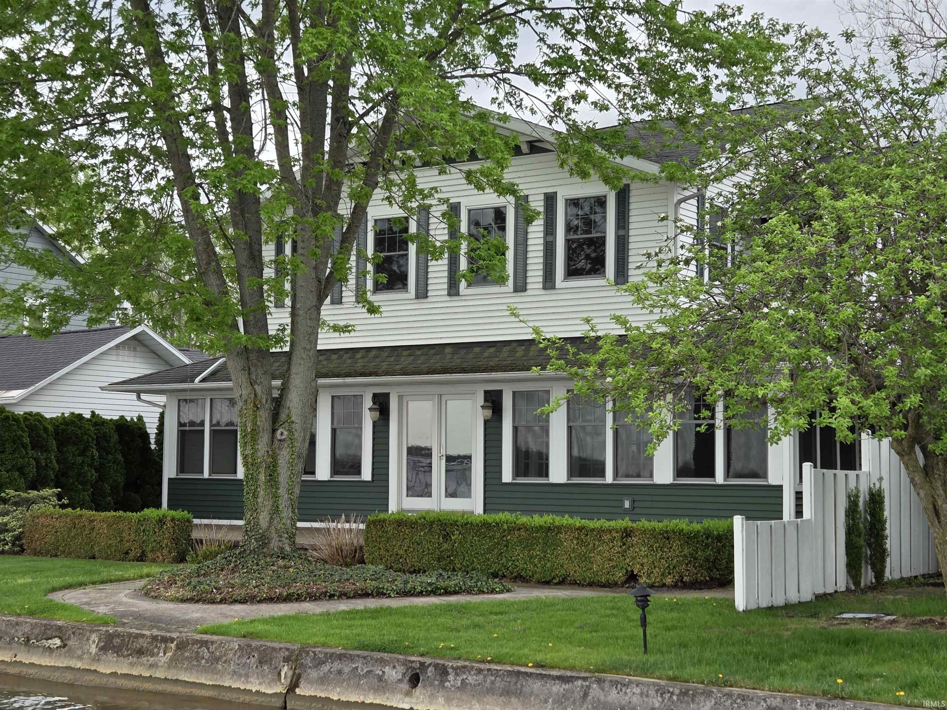 Image 0: Two-story residence featuring white siding with contrasting dark green shutters and lower-level siding, Front Of Structure Image 0: Two-story residence featuring white siding with contrasting dark green shutters and lower-level siding, Front Of Structure