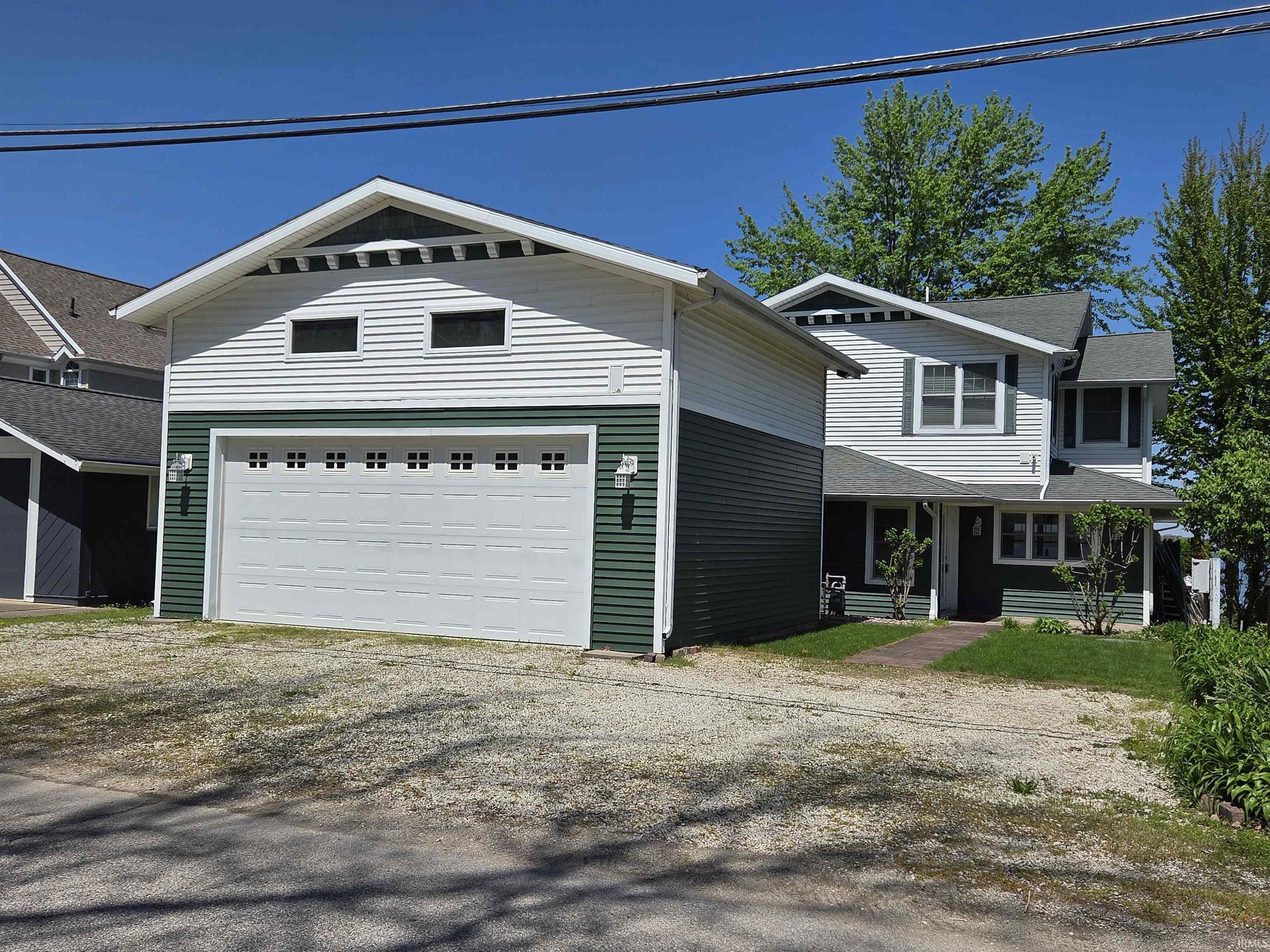 Image 2: Two-story residence featuring white and dark green horizontal siding, a two-car garage with transom windows, and a covered entry porch, Front Of Structure Image 2: Two-story residence featuring white and dark green horizontal siding, a two-car garage with transom windows, and a covered entry porch, Front Of Structure