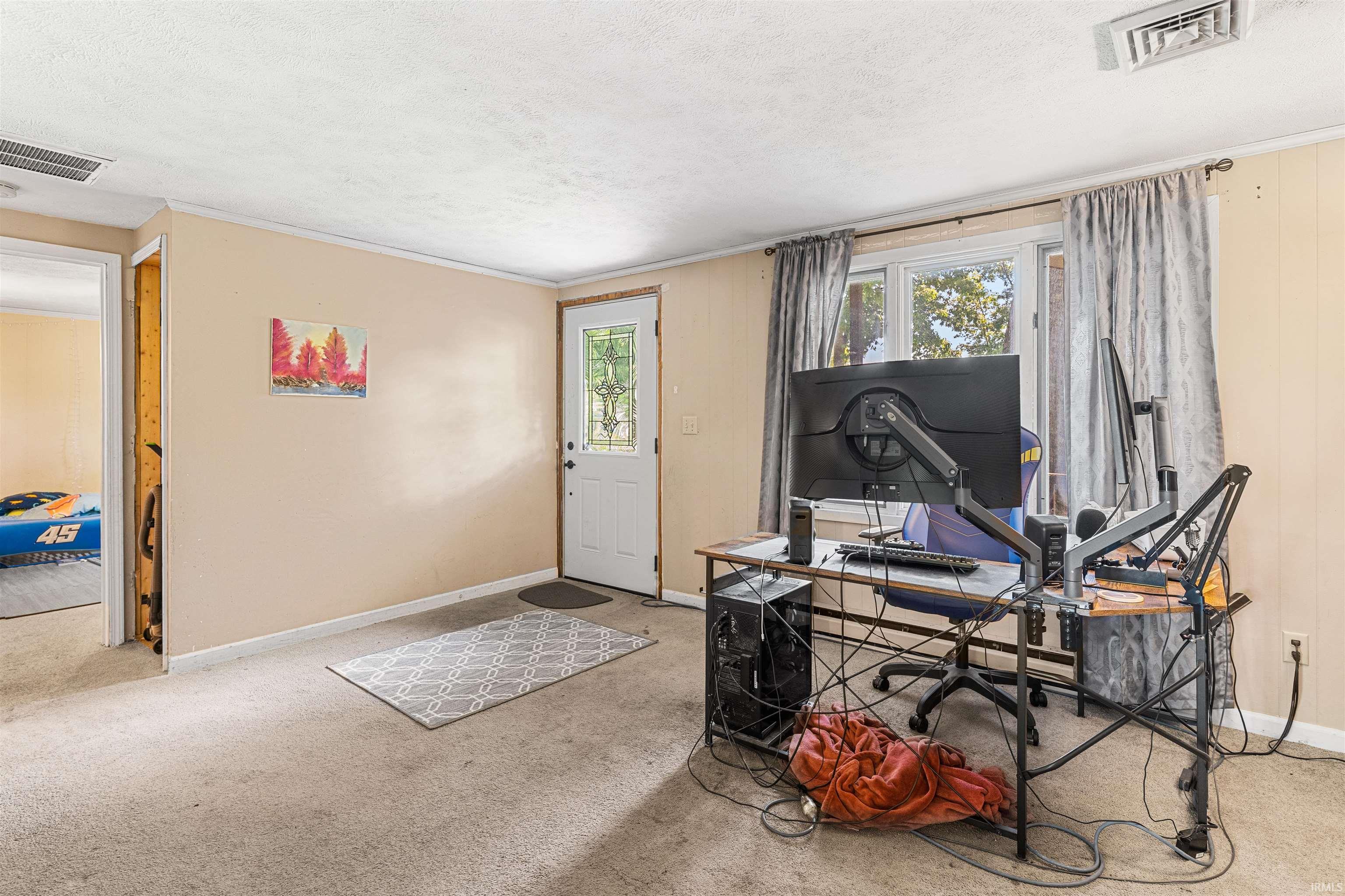 Image 1: Carpeted interior space featuring a white entry door with a decorative glass insert, a large window with natural light, and light-colored wall paneling, Office Image 1: Carpeted interior space featuring a white entry door with a decorative glass insert, a large window with natural light, and light-colored wall paneling, Office