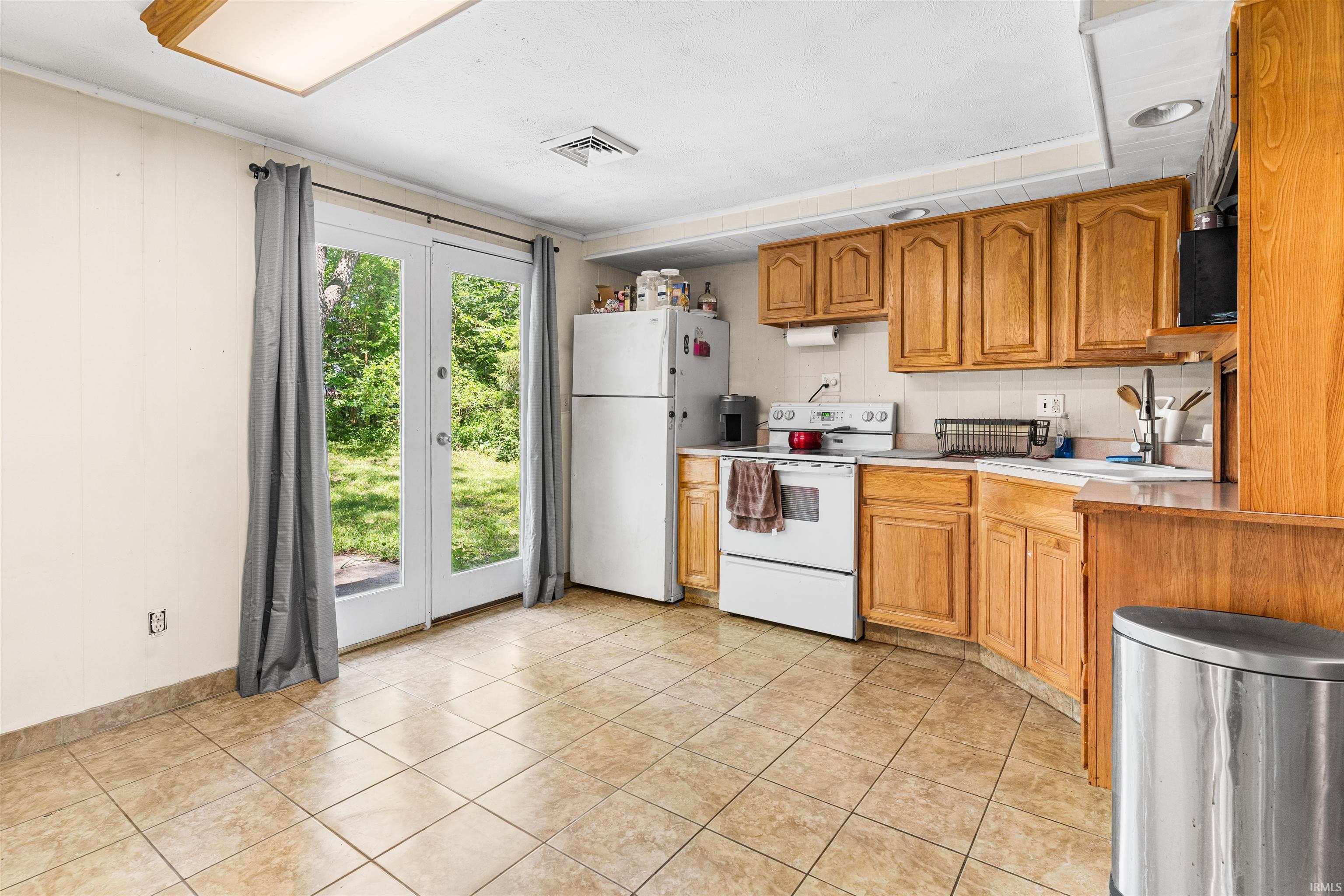 Image 2: Kitchen featuring light wood cabinetry, a white tile backsplash, and light-toned tile flooring, Kitchen Image 2: Kitchen featuring light wood cabinetry, a white tile backsplash, and light-toned tile flooring, Kitchen