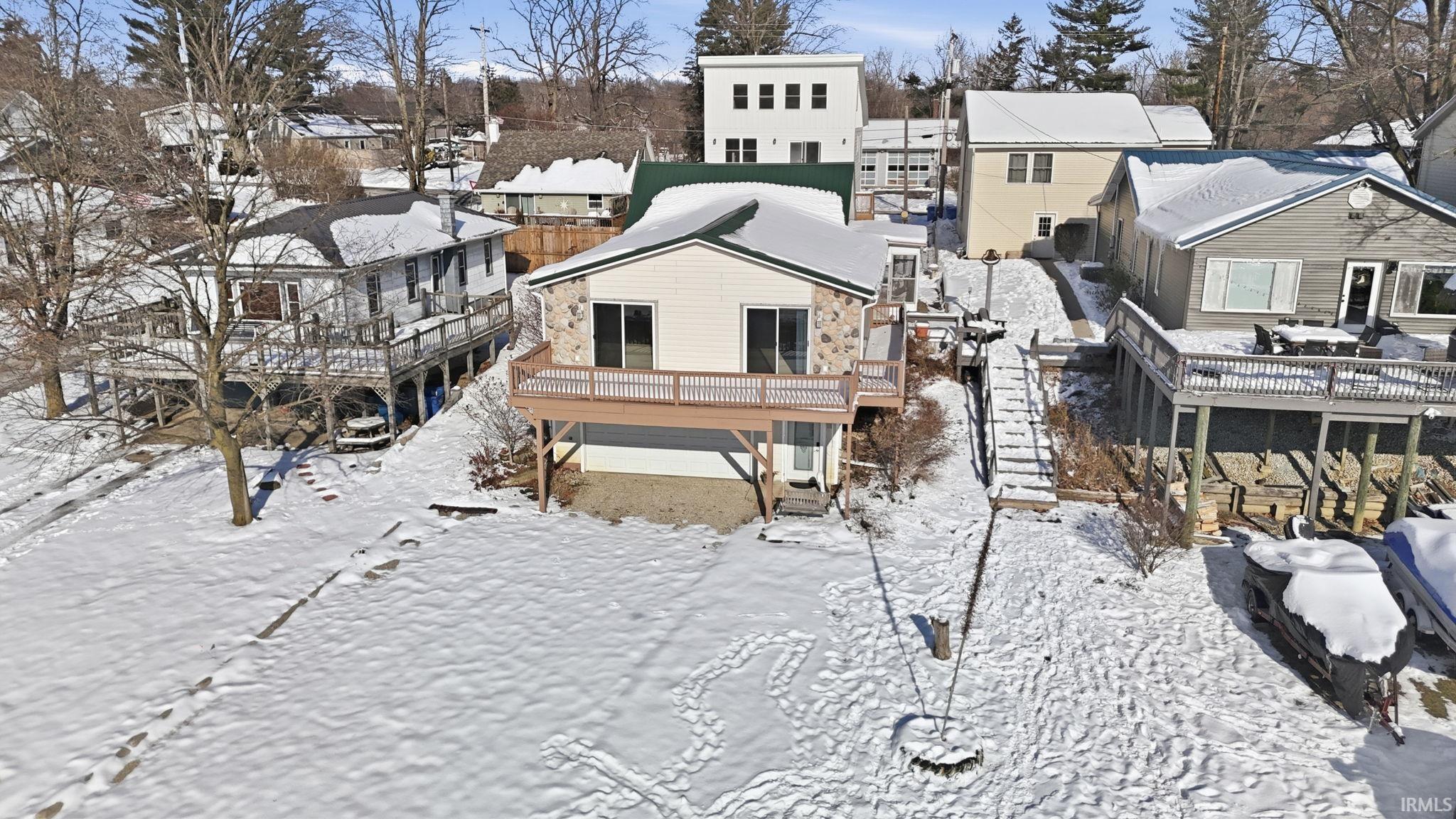 Image 0: Snow covered house with a wooden deck, a residential view, and stairs, Back Of Structure Image 0: Snow covered house with a wooden deck, a residential view, and stairs, Back Of Structure