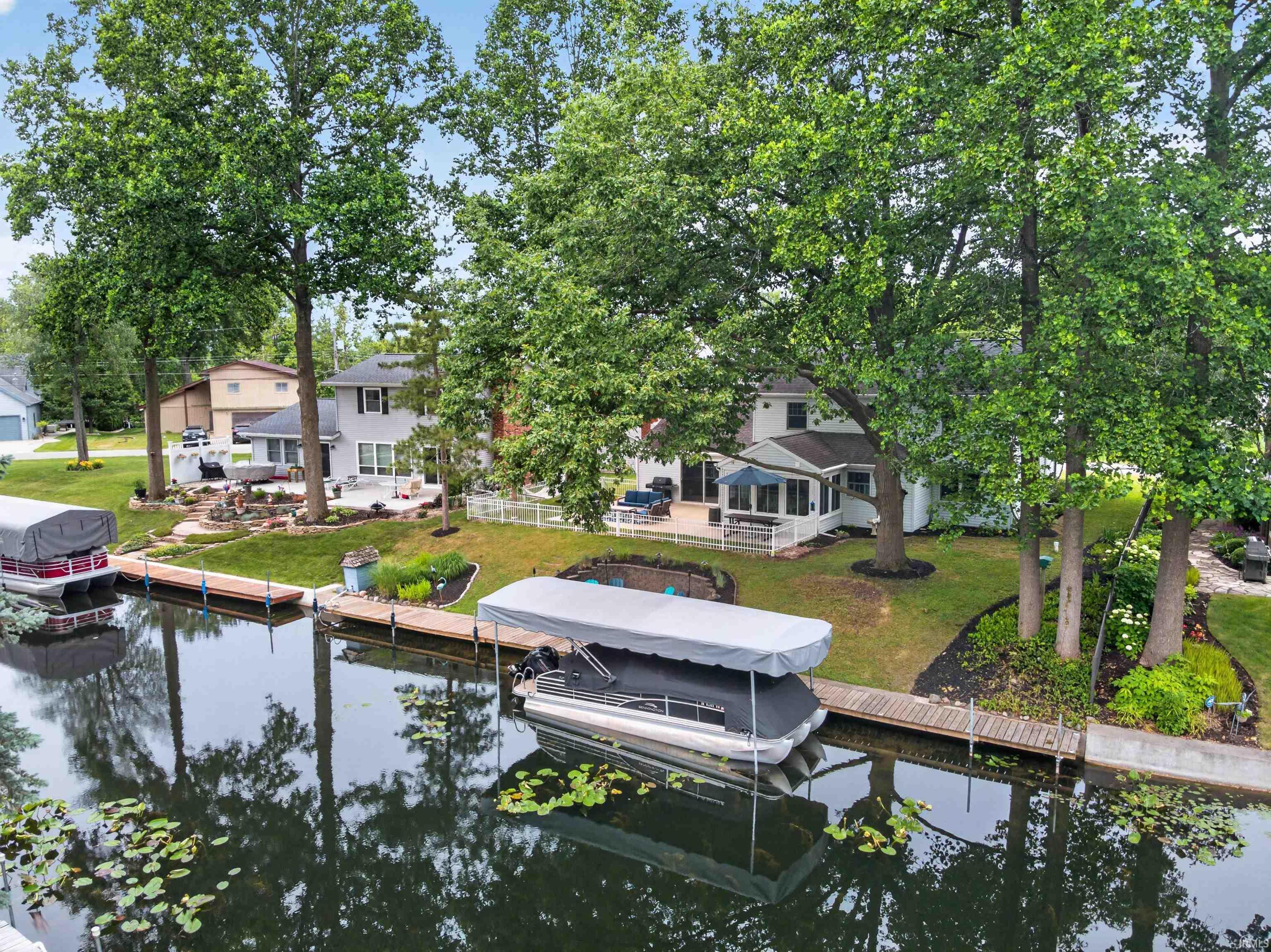 Image 2: Waterfront property featuring a private boat dock with a covered slip, a spacious patio, an enclosed porch, mature trees, and landscaped grounds, Dock