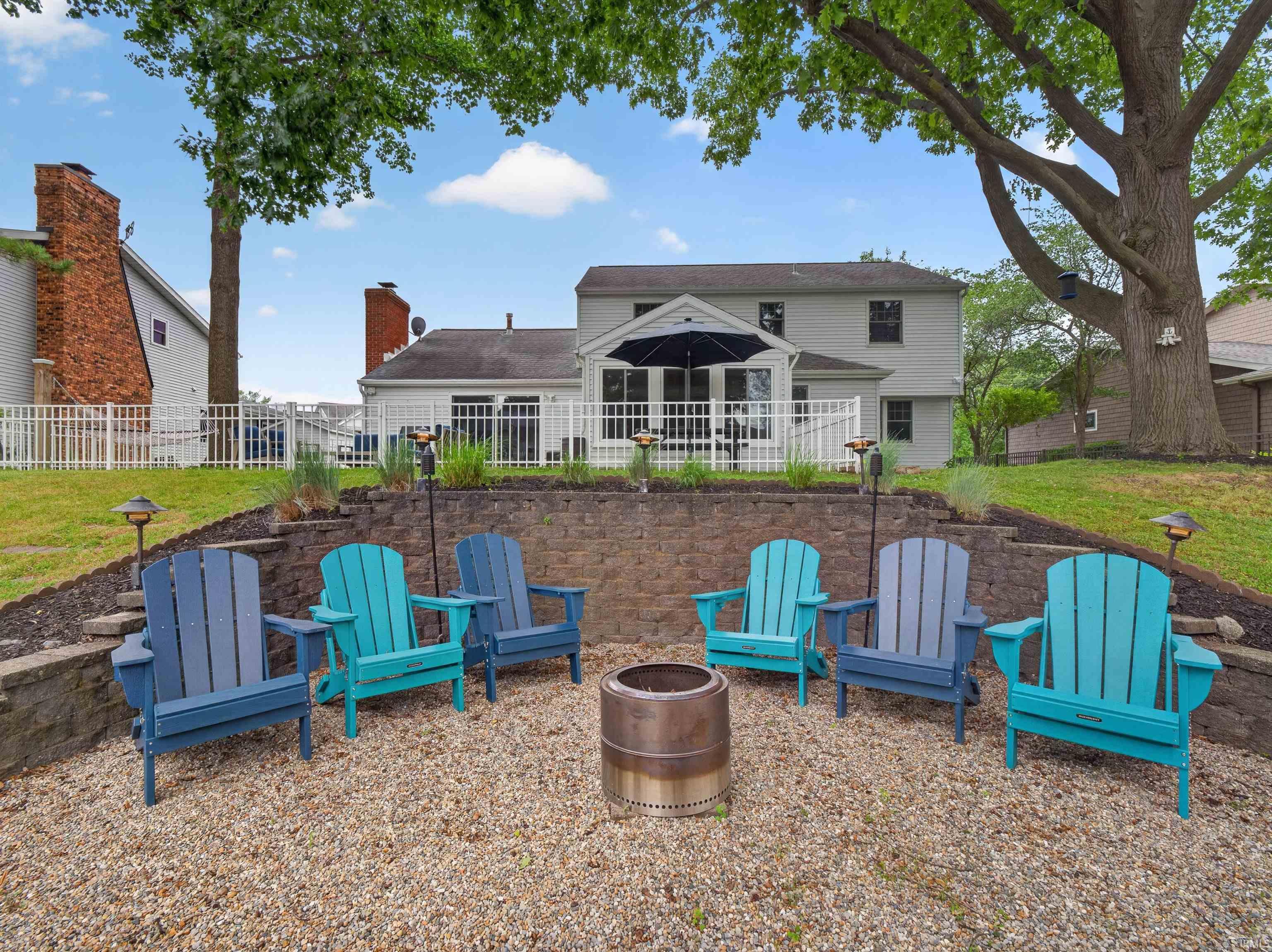 Image 3: Gravel patio featuring a built-in fire pit, surrounded by a tiered stone retaining wall, Back Of Structure