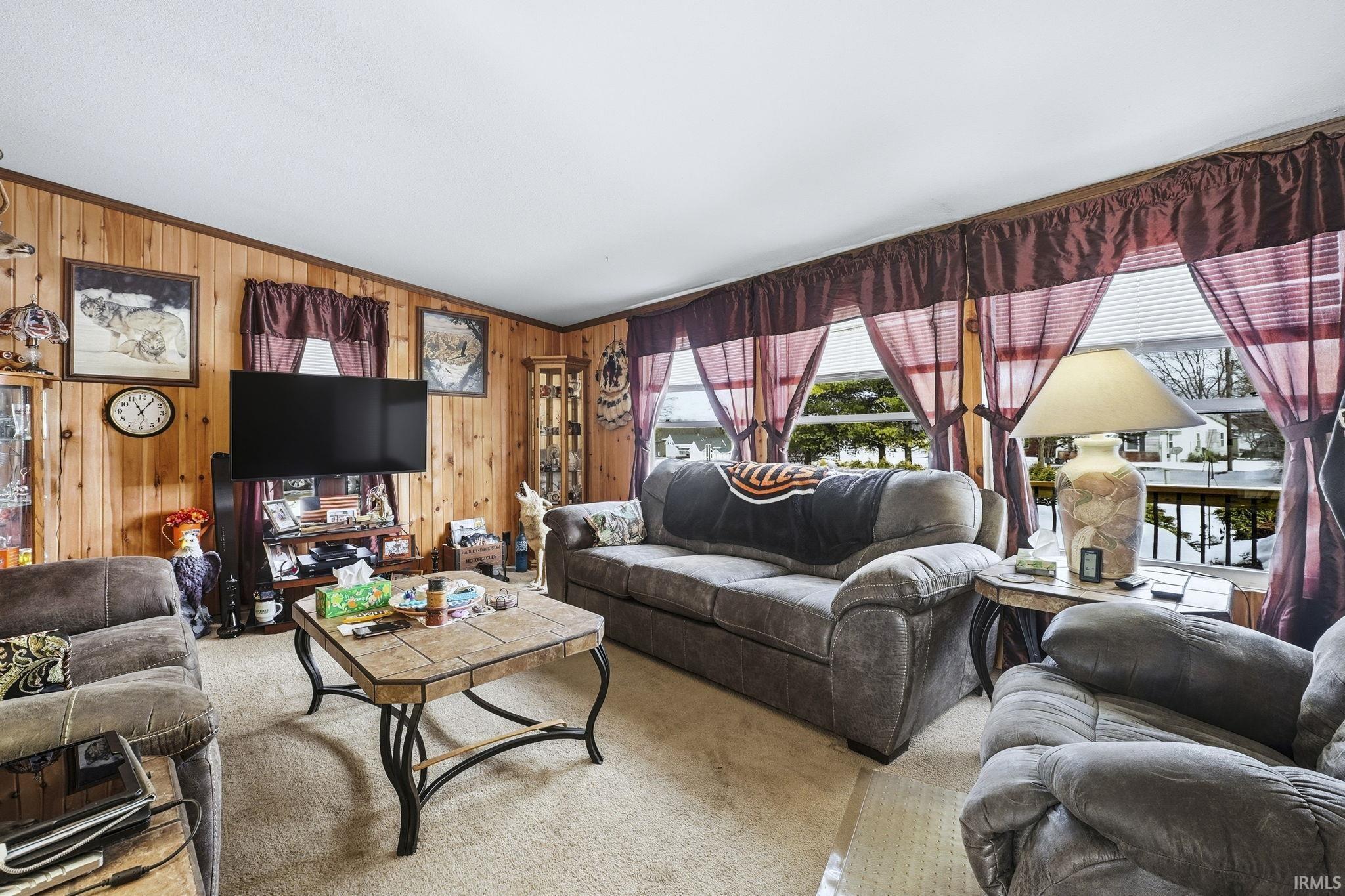 Image 3: Living room with carpet, vaulted ceiling, wood walls, and crown molding, Living Room