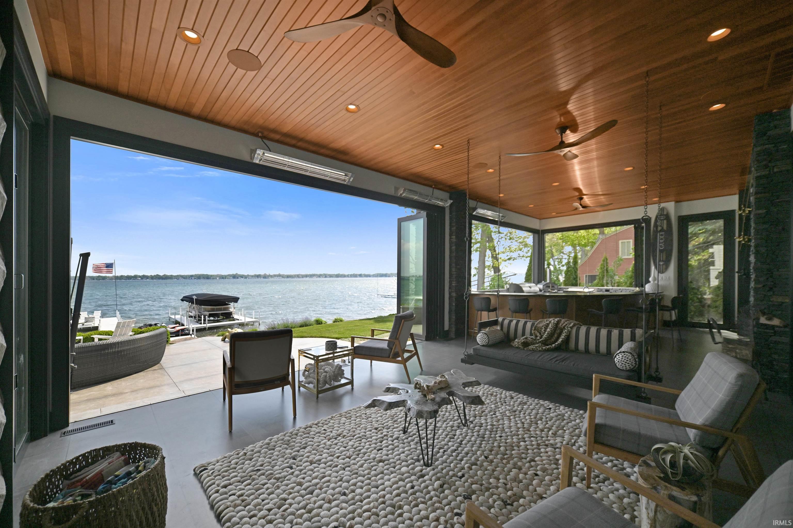 Image 0: Expansive waterfront living space featuring a wood-panel ceiling with recessed lighting and ceiling fans, Sun Room Image 0: Expansive waterfront living space featuring a wood-panel ceiling with recessed lighting and ceiling fans, Sun Room