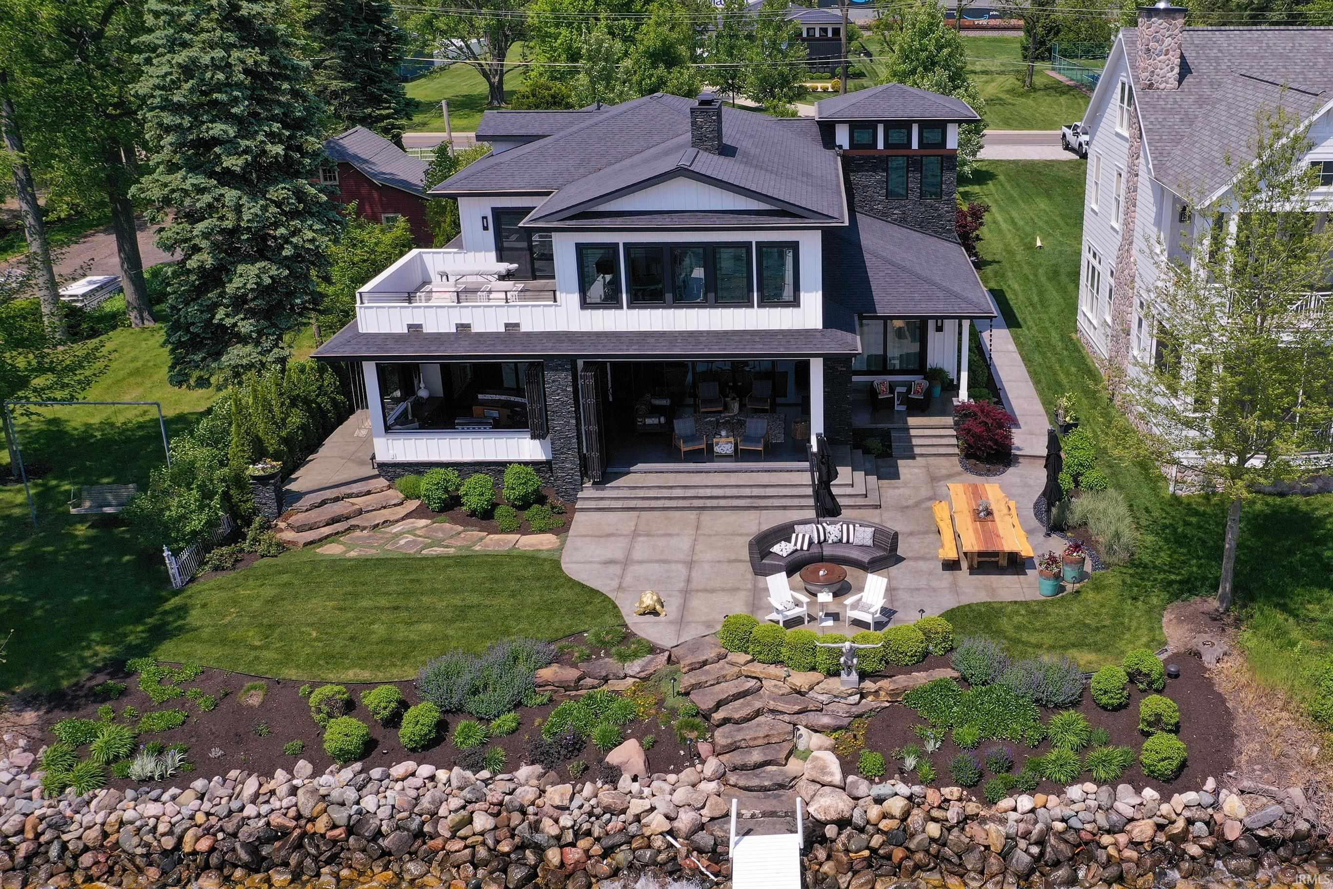 Image 1: Modern waterfront residence featuring a multi-level outdoor living space, large upper-level balcony, and expansive lower-level patio, Back Of Structure Image 1: Modern waterfront residence featuring a multi-level outdoor living space, large upper-level balcony, and expansive lower-level patio, Back Of Structure