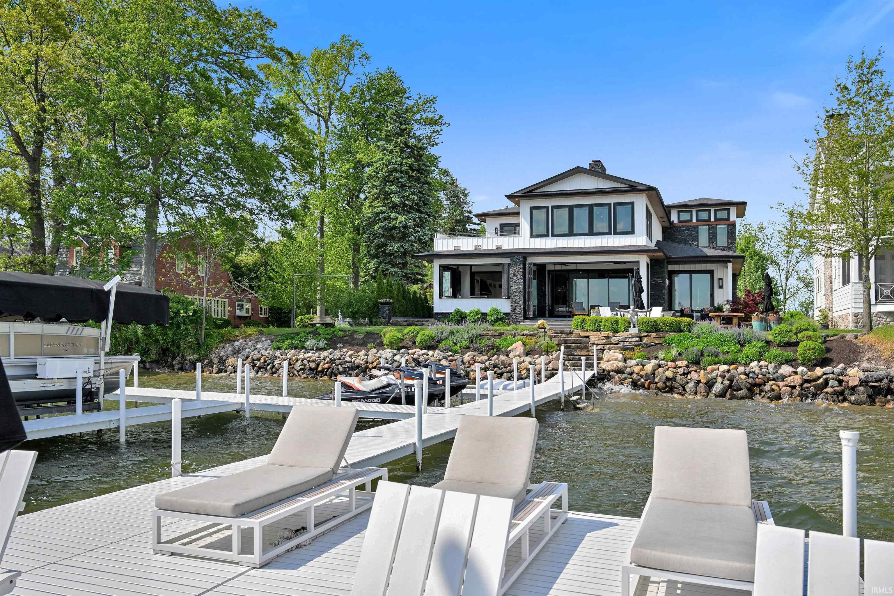 Image 2: Waterfront property featuring a private dock system, a contemporary house with dark-framed windows, a stone and white siding exterior, and a terraced landscape with natural rock hardscaping, Dock Image 2: Waterfront property featuring a private dock system, a contemporary house with dark-framed windows, a stone and white siding exterior, and a terraced landscape with natural rock hardscaping, Dock